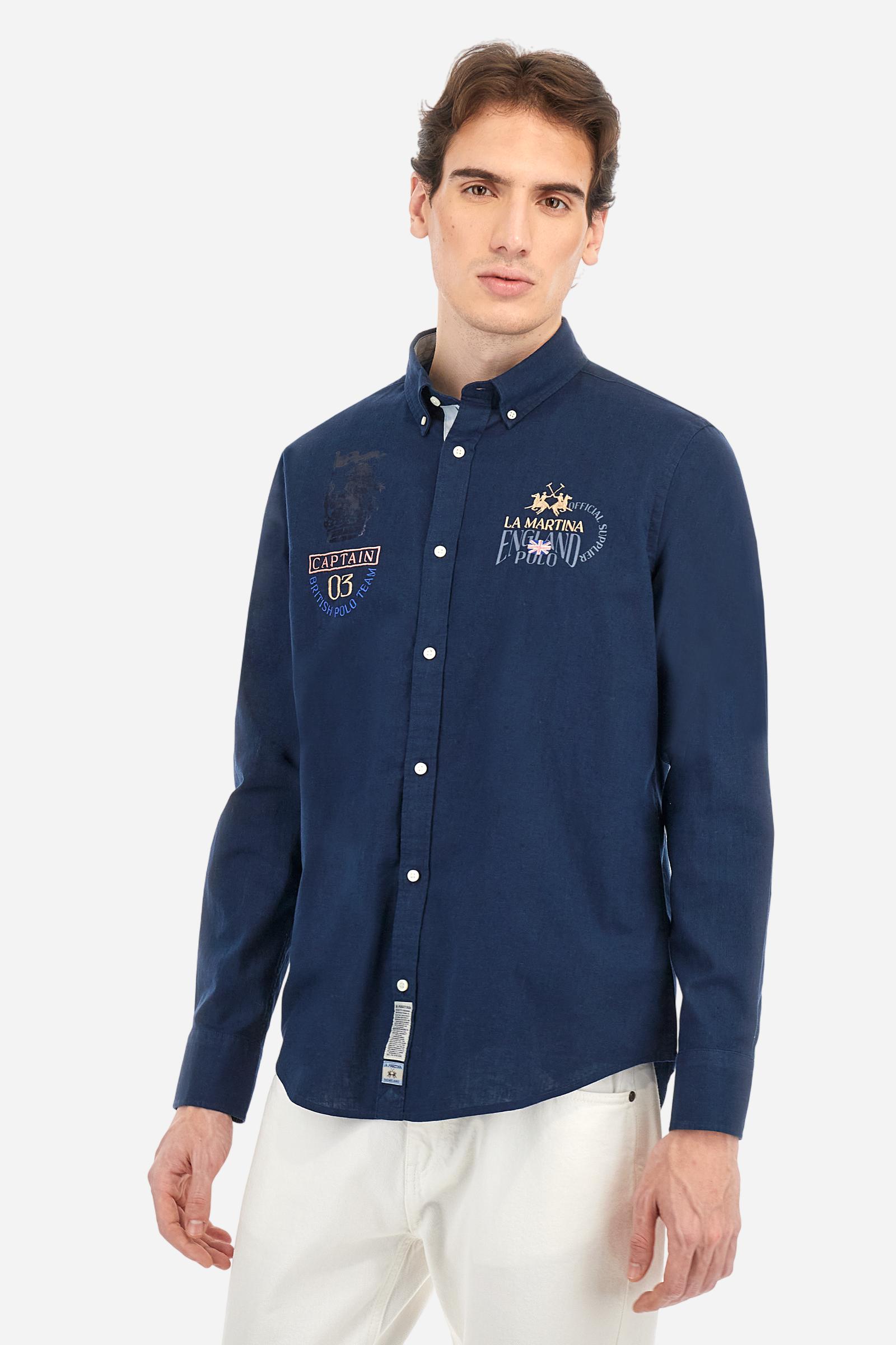 Men's long-sleeved single-colour shirt made of cotton and linen canvas. Button-down collar. Featuring details on the inside of the collar and opening in contrasting colour printed fabrics. The front graphics and logo are embroidered with contrasting colour threads. The fit is regular. The model is wearing a size L. - Navy