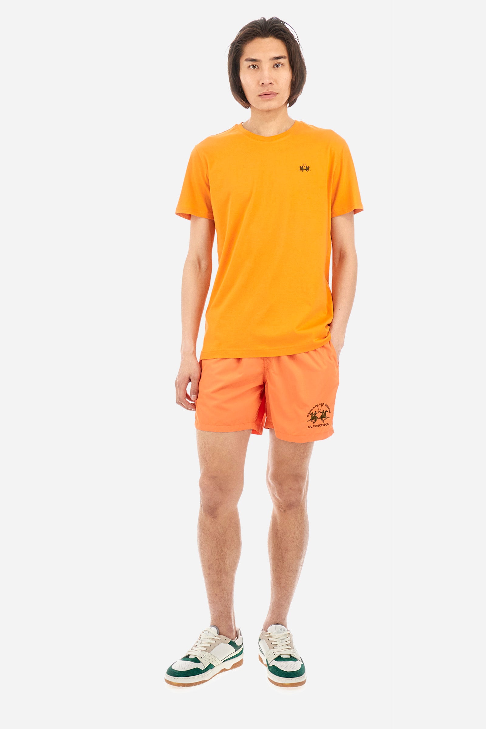 Single-colour men's swimming shorts, made of synthetic fabric. Featuring a drawstring and tie with "La Martina" lettering. Double welt pocket on the front. Closed pocket on the back. Mesh lining. Large logo embroidered on the front. The fit is regular. The model wears a size L. - Celosia Orange