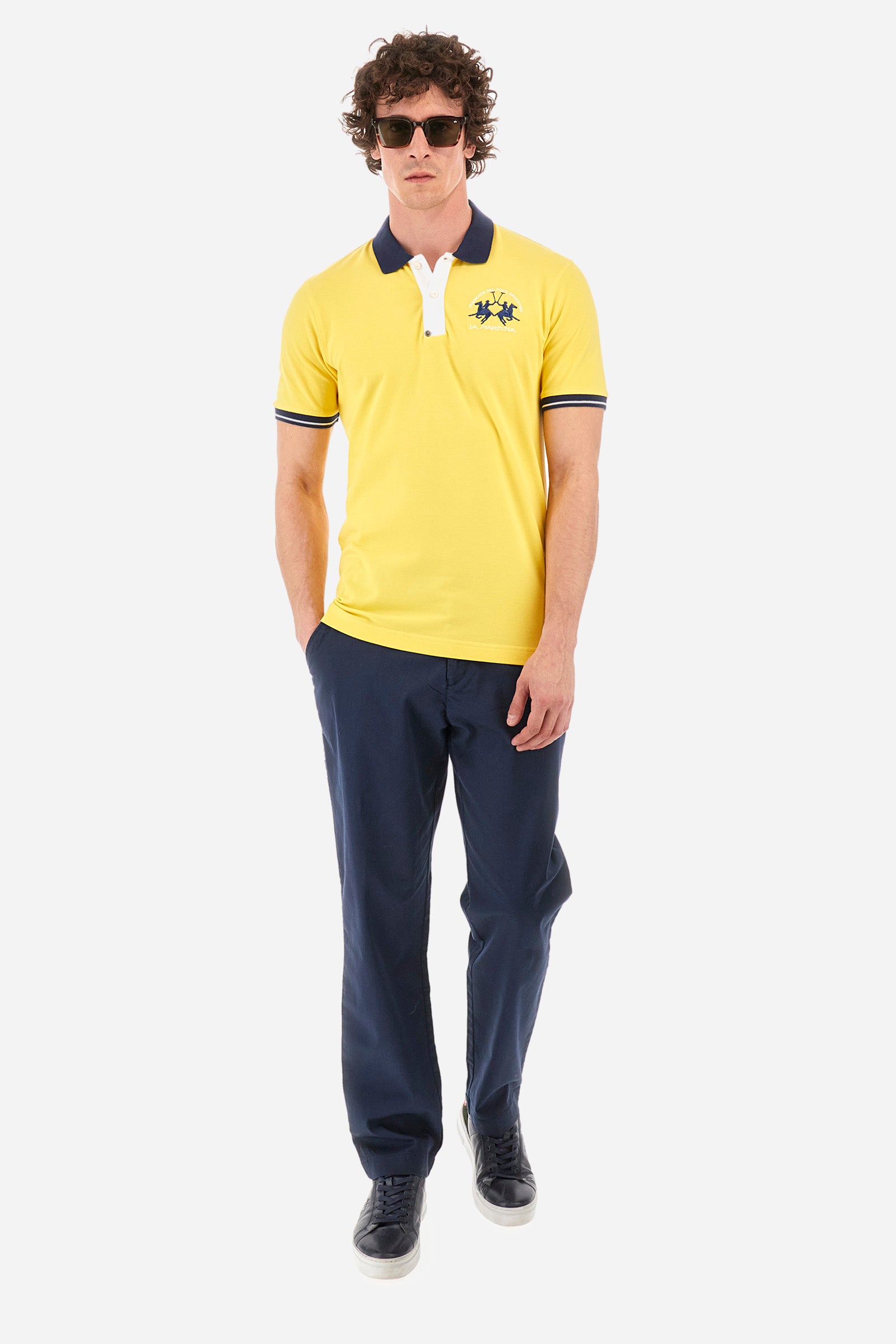 Men's single-colour short-sleeved polo in elasticated cotton. Fastens with two contrasting buttons. Ribbed collar and armholes in different shades. The "La Martina" lettering can be found under the collar. A large logo is embroidered on the chest. The fit is slim. The model wears a size L. - Aspen Gold