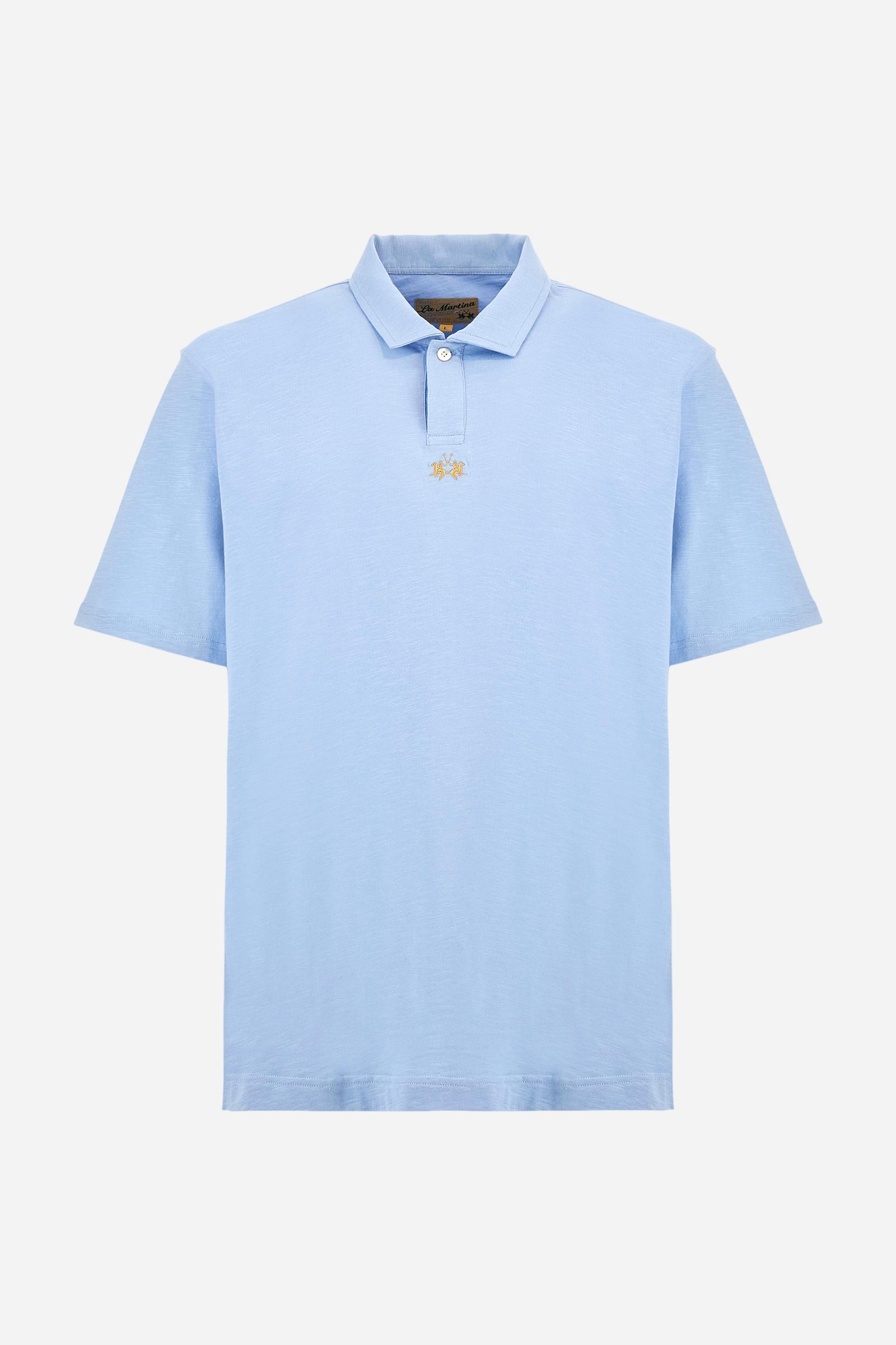 Men's short-sleeved polo shirt in a single colour, made of 100% cotton slub jersey. Fastens with a button. A fabric patch representing the garment's certificate is sewn onto the back. The logo is embroidered in contrast under the opening on the front. Comfort fit. The model is wearing a size L. - Vista Blue