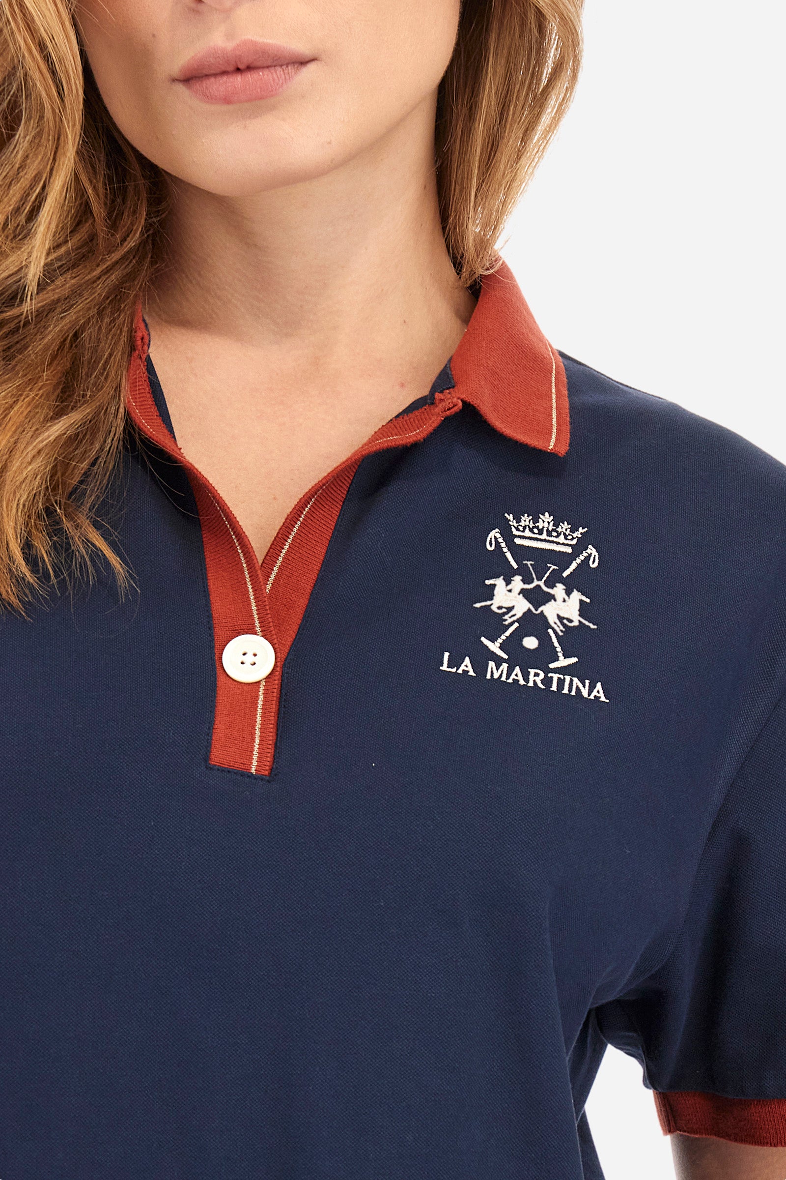Women’s polo with short sleeves in solid color with contrasting details of the Academy Polo line. Made of stretch cotton. V-neck and armhole hem in contrasting shades. Single button closure. Ribbed neckline, collar and armhole. On the back is sewn the name and logo of the brand. On the back there is a metal plate with the logo applied on a colored strip. The fit is regular. The model wears a size 2. - Navy