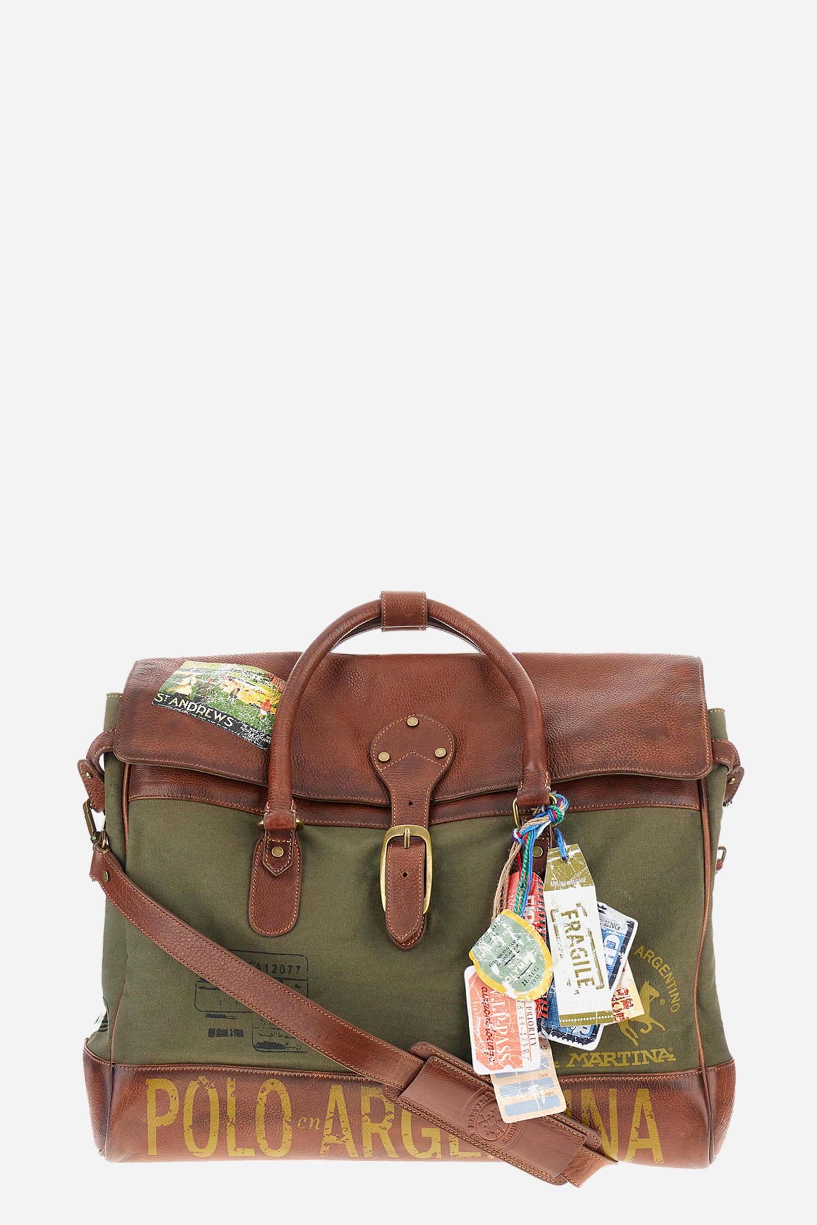 Unisex bicolor duffel bag made of 100% leather. Snap button closure. Equipped with two handles and a removable shoulder strap. Inside, there is a zippered pocket. Iconic design of the brand, embellished with writings, patches, and applied labels throughout the accessory. The La Martina logo is on the back. Dimensions (width x height x depth) 68x43x26 cm. - Military Olive