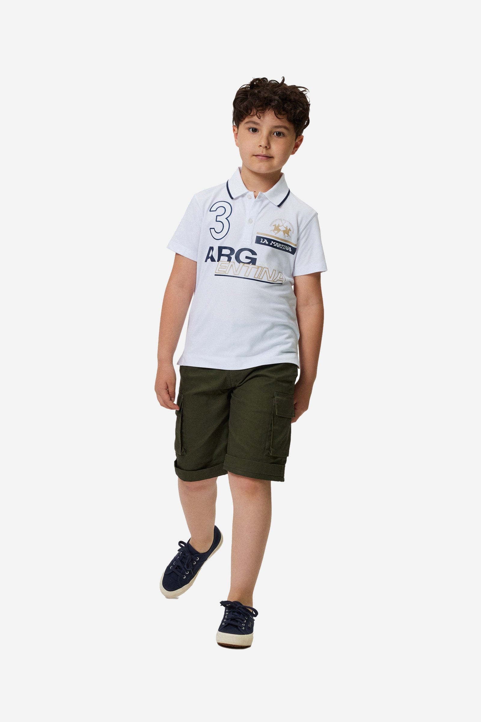 Boys' single-colour polo shirt made of pique cotton. Two-button fastening. Profiled collar with contrasting colour thread. There are various embroideries and rubberised prints on the front of the garment. The logo is on the chest, left side. - Optic White