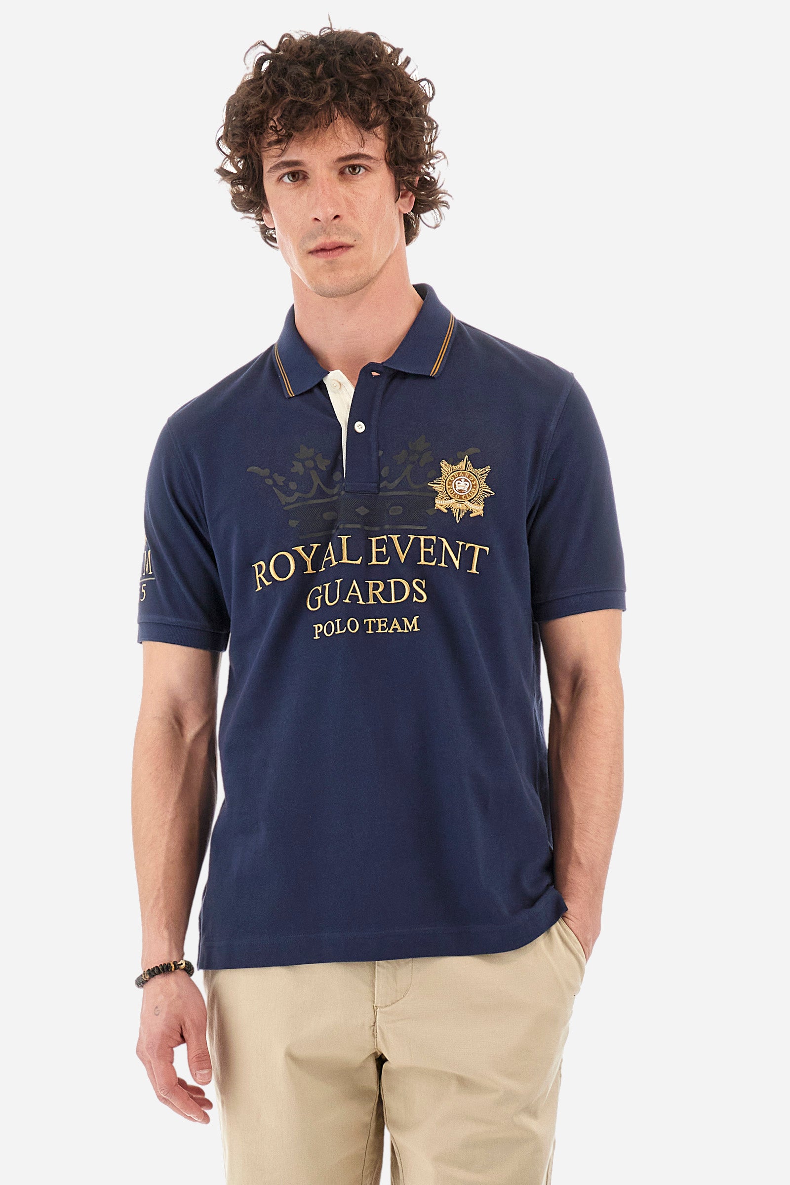 Men's single-colour short-sleeved polo shirt in 100% cotton. Two-button fastening. Collar with two contrasting stripes and ribbed armholes. On the front we find lettering and the symbol representing the Guards line. The brand's initials, the number 55 and the logo are embroidered on one of the sleeves. The fit is regular. The model wears a size L. - Navy