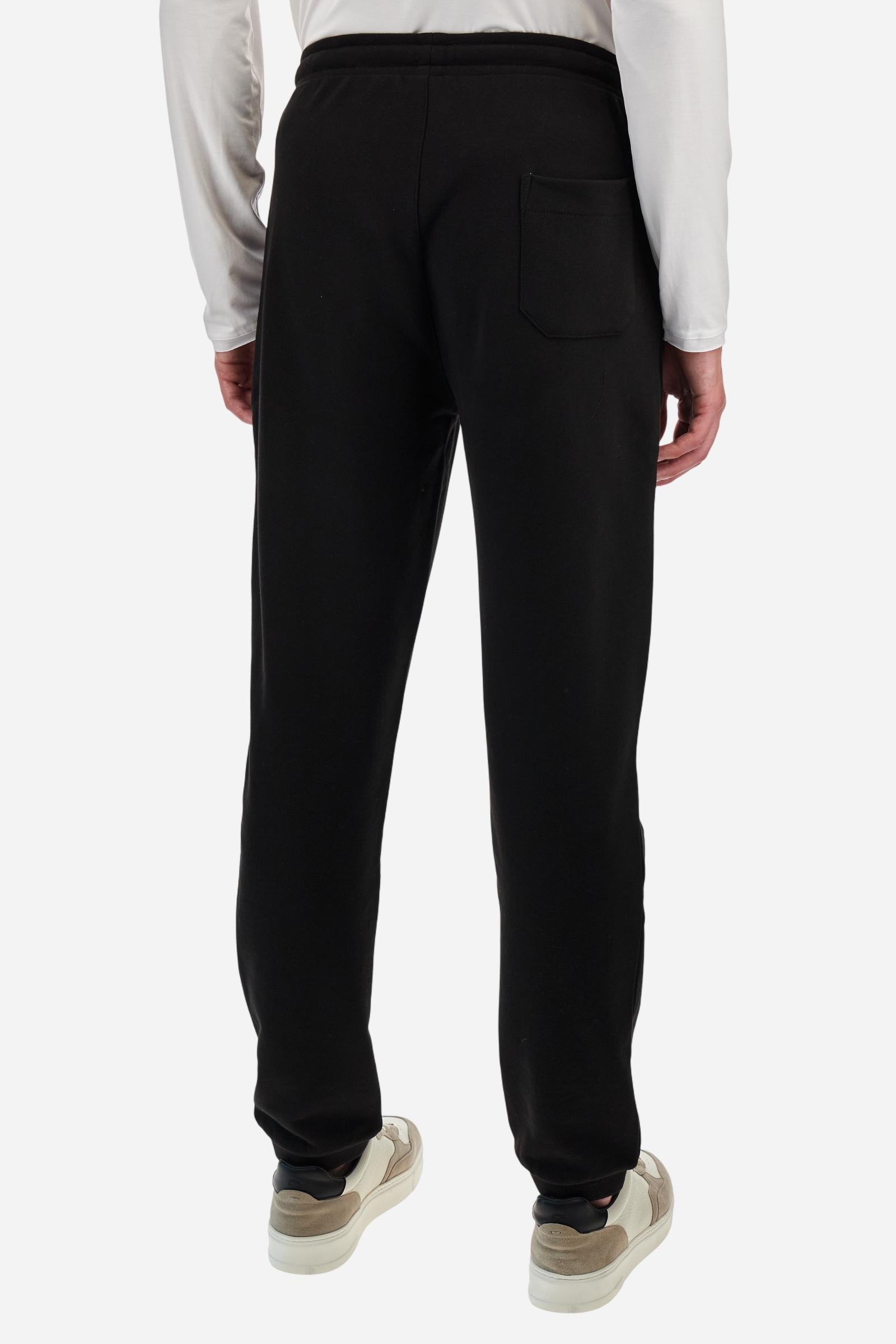Single-colour men's jogging trousers in a French terry cotton sweat fabric. Removable and adjustable waistband with drawstring. American pockets at the sides. An additional patch pocket is applied on the back. The logo is embroidered in a colour-contrasting thread on the front, left side. The fit is regular. The model is wearing a size L. - Black