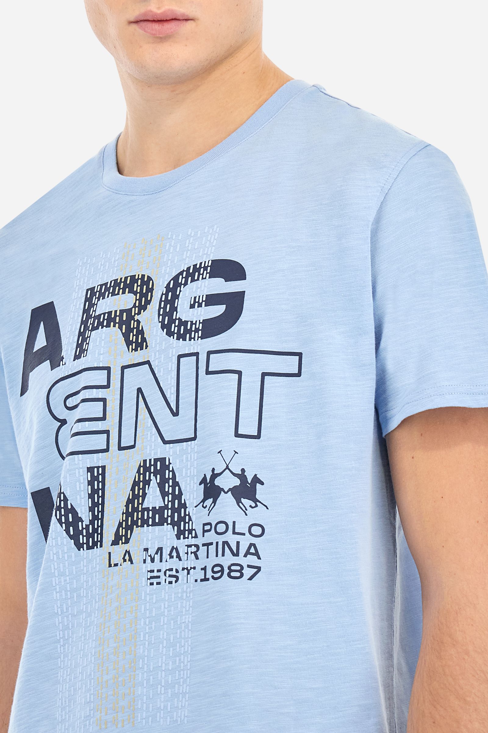 Men's T-shirt with plain sleeves, made of slub jersey. Ribbed crew neck. The graphic on the chest is a multicoloured rubberised print. The dotted effect is also a slightly raised embroidery effect print. The logo is printed on the front. Regular fit. The model is wearing a size L. - Vista Blue