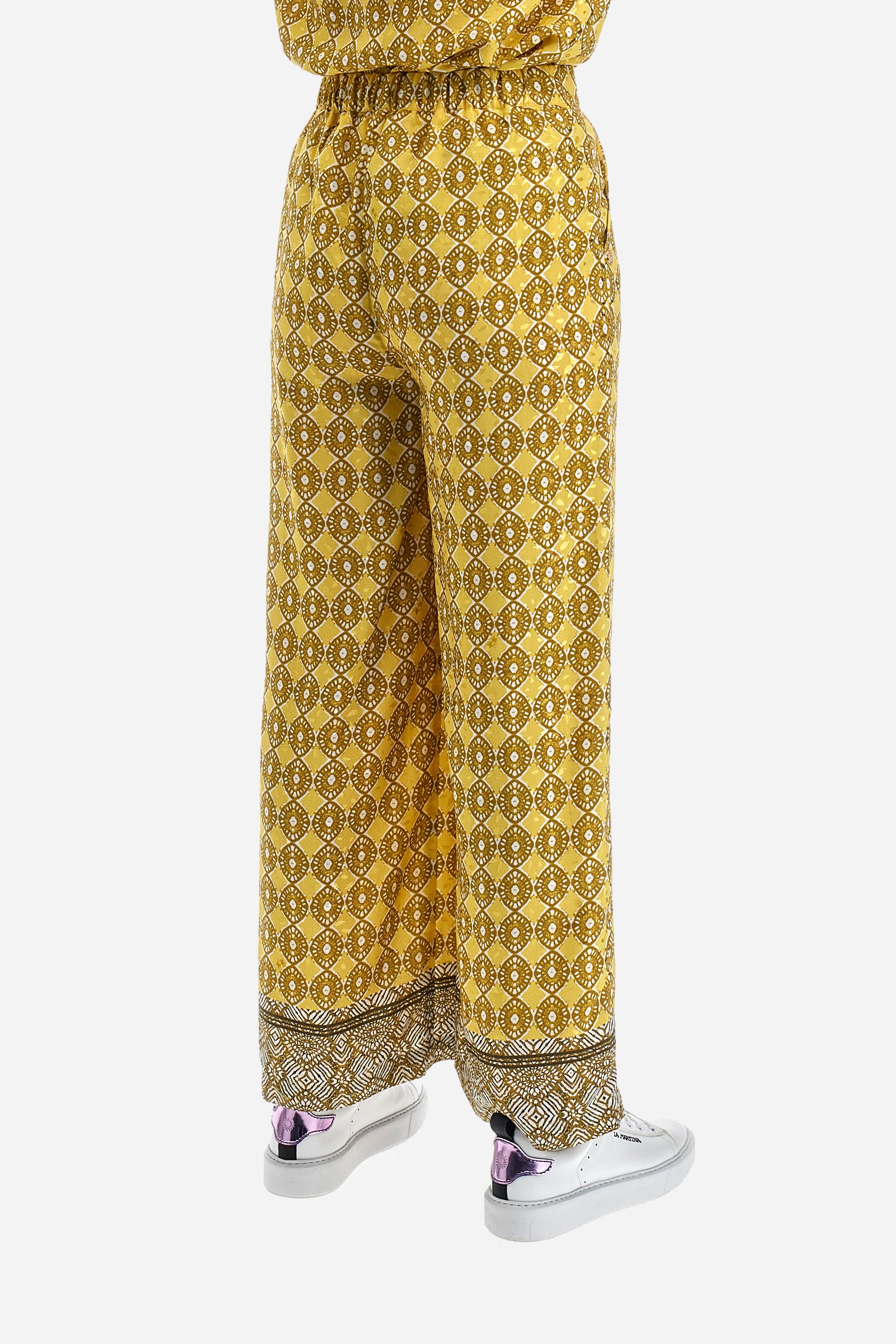 Women's palazzo trousers with geometric prints, made in a synthetic fabric. Elasticated waistband. There are two open front pockets. A metal plate with the logo is sewn on the front. The fit is regular. The model wears a size 2. - Goldfinch/Arrow/Whit