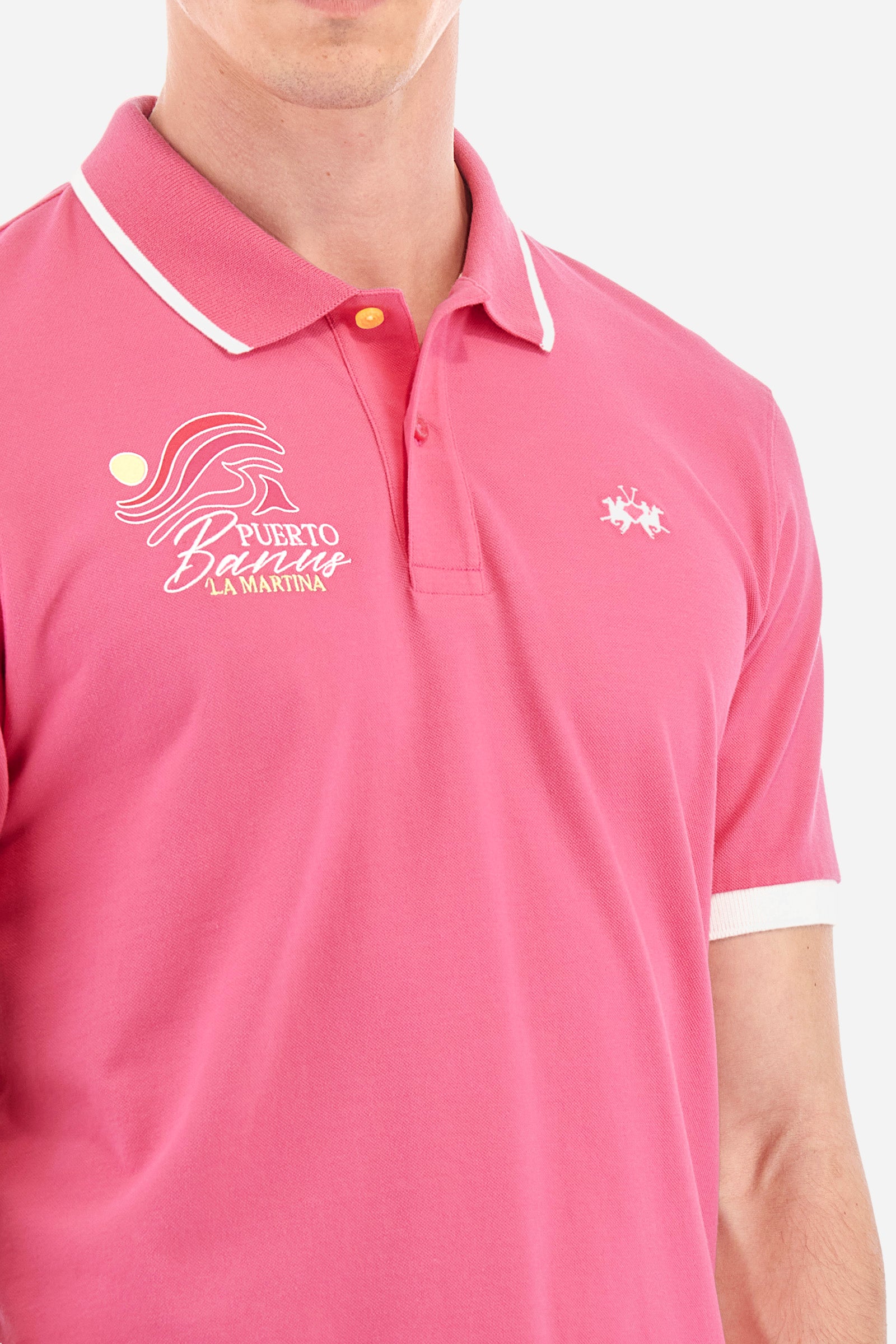 Men's short-sleeved single-colour polo shirt in elasticated cotton. Two-button fastening. With a profiled and ribbed collar and armholes. On the chest we find stylised waves with lettering. The back of the collar features the "La Martina" lettering. The logo is embroidered on the front. The fit is regular. The model wears a size L. - Hot Pink