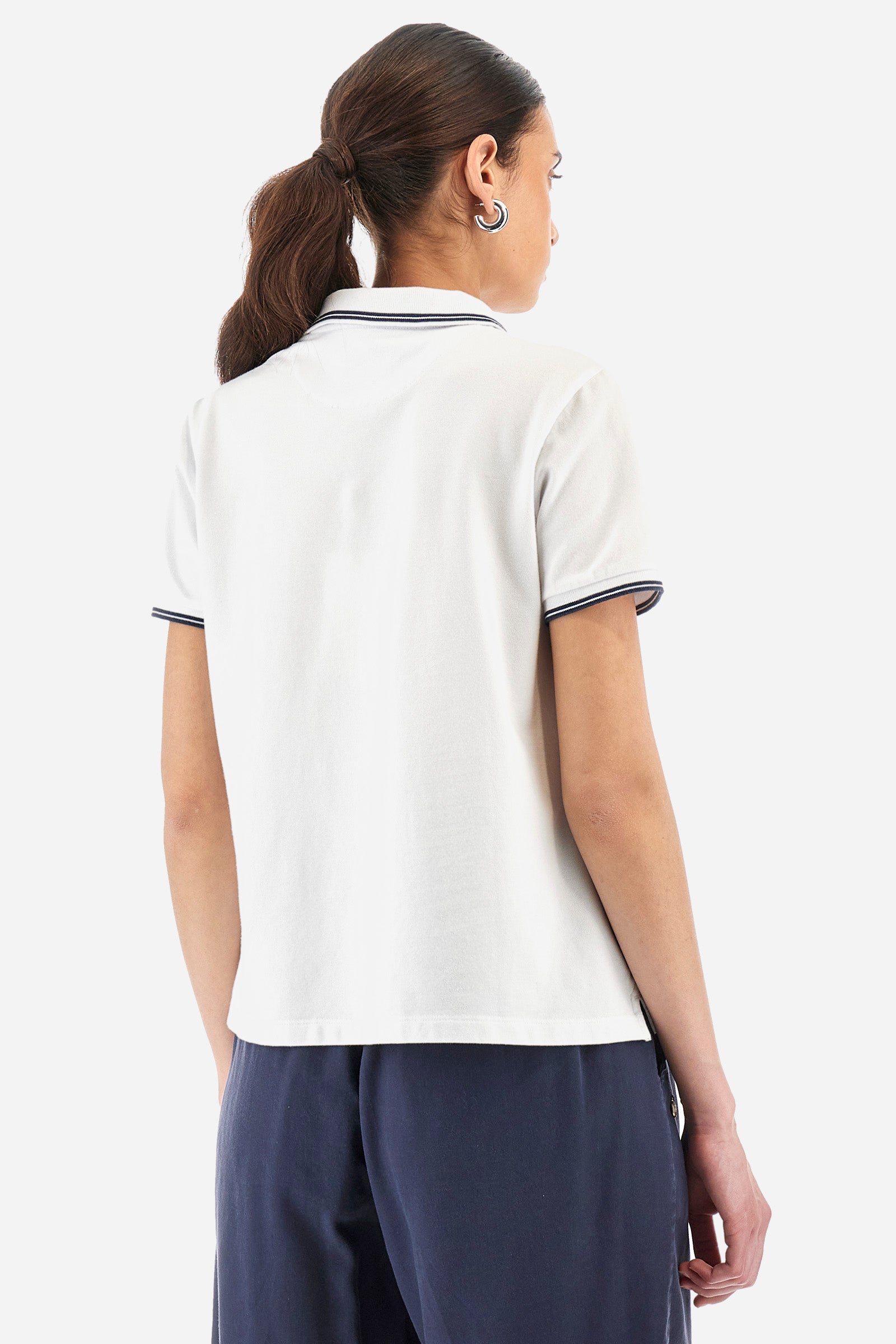 Women’s polo with short sleeves in solid color, made of stretch cotton. 5-button closure, ribbed collar and crew sleeves, where contrasting stripes are sewn. Side slits. On the front are embroideries with symbols and initials of the brand, recalling the capsule collection Polo Club Grand Hotel. The logo is embroidered on a contrasting sleeve. The fit is regular. The model wears a size 2. - Optic White