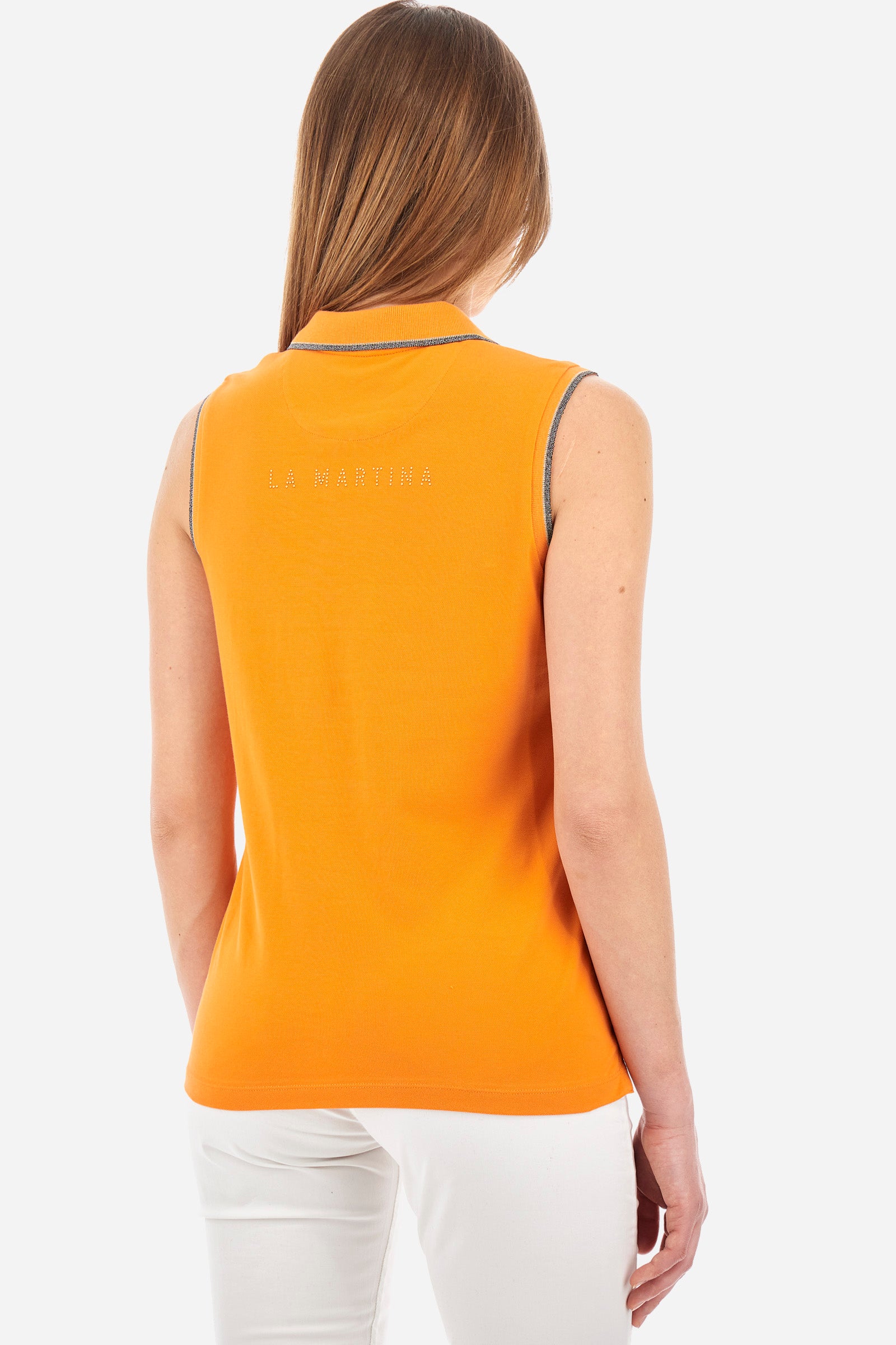 Women’s sleeveless polo shirt in solid color, made of stretch cotton. V-neck and 2 button closure. Collar and crew sleeves profiled and ribbed. Side slits. On the back there is the inscription "La Martina" composed of small rhinestones. The logo is present on the front. The fit is regular. The model wears a size 2 . - Celosia Orange