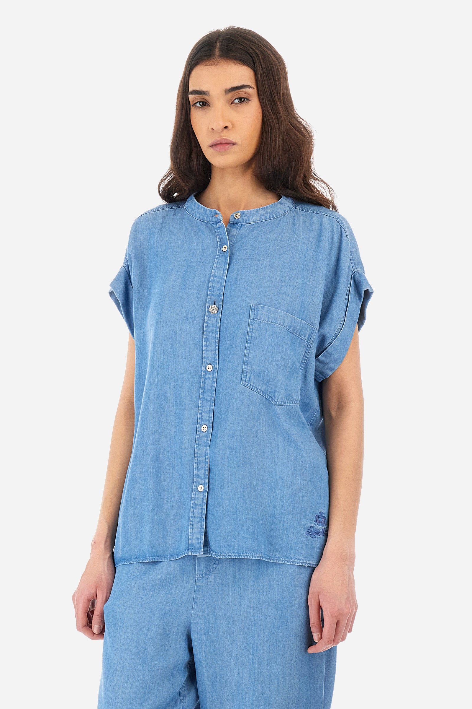 Women's short-sleeved denim shirt, made of ecological fabric. Mandarin collar. There is an open pocket on the chest. Featuring a jewel button. The front features the logo and "La Martina" lettering. The fit is regular. The model wears a size 2. - Medium Indigo Denim