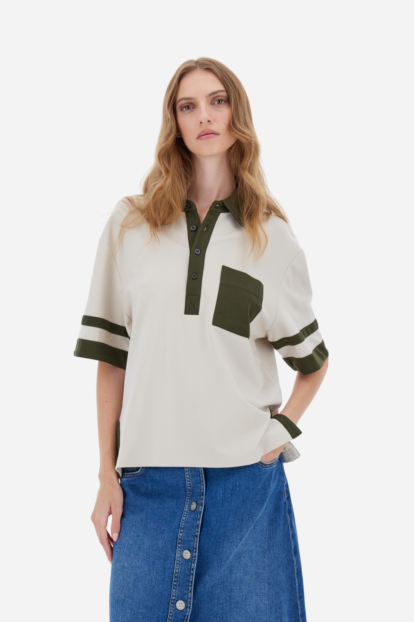 Women’s short-sleeve polo shirt in high-quality solid-colour viscose blend interlock. Classic collar with deep three-button placket, contrast fabric details on body and sleeves. Large embroidered logo on the back. Boxy, straight fit at the hips for a modern and comfortable silhouette. The model wears size L. - Creme Brulè/Kombu Gr