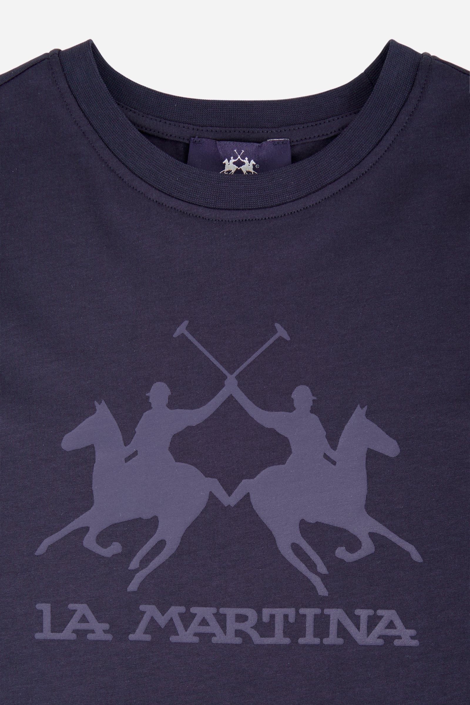 Short-sleeved T-shirt for boys made from soft 100% cotton jersey in a solid colour. The style features a regular fit and tonal ribbed crew neck. The maxi front print, featuring the iconic crossed polo players logo and La Martina lettering, gives the garment strong visual impact and a bold sporty style. - Navy