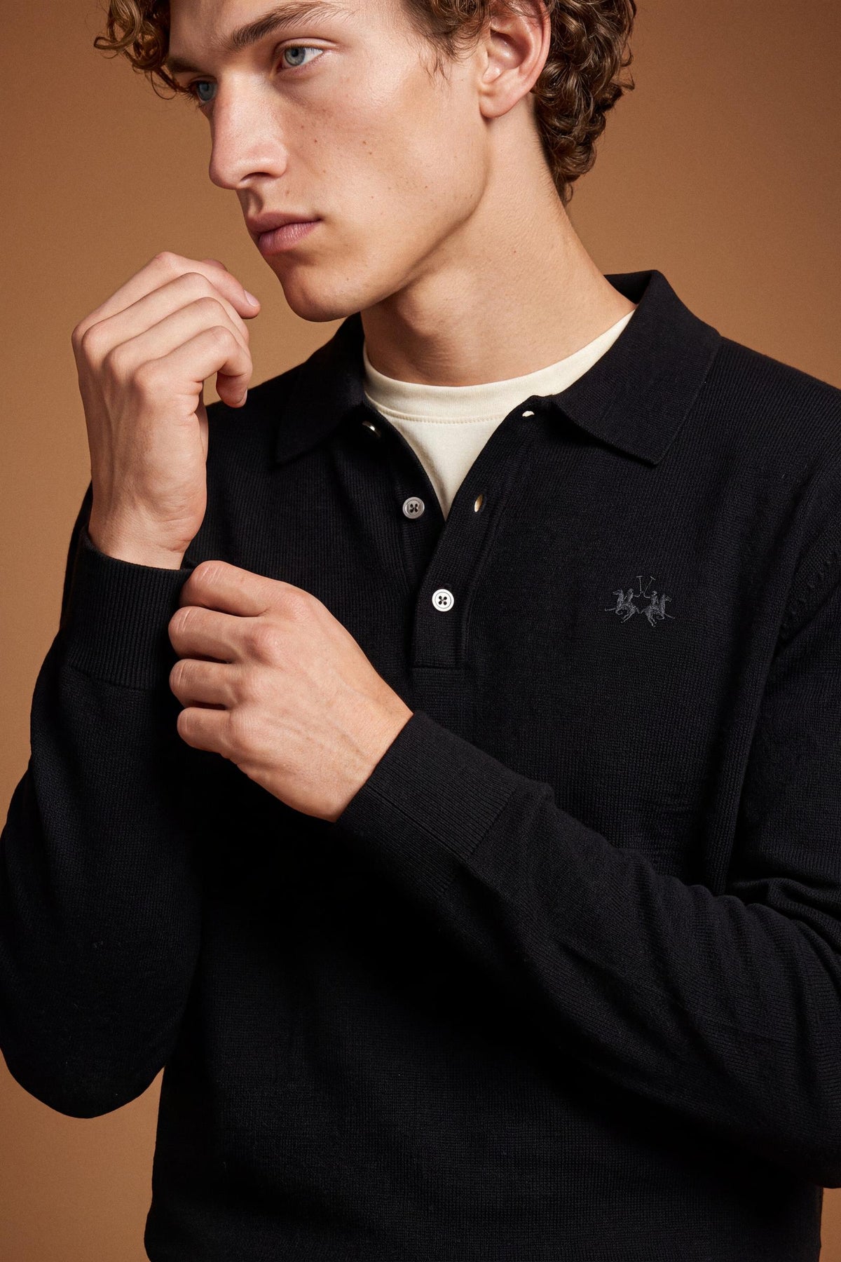 Men's long-sleeve polo made from 100% merino wool offers a comfortable fit, classic knitted collar, ribbed cuffs, and a subtle embroidered logo on the chest. - Black