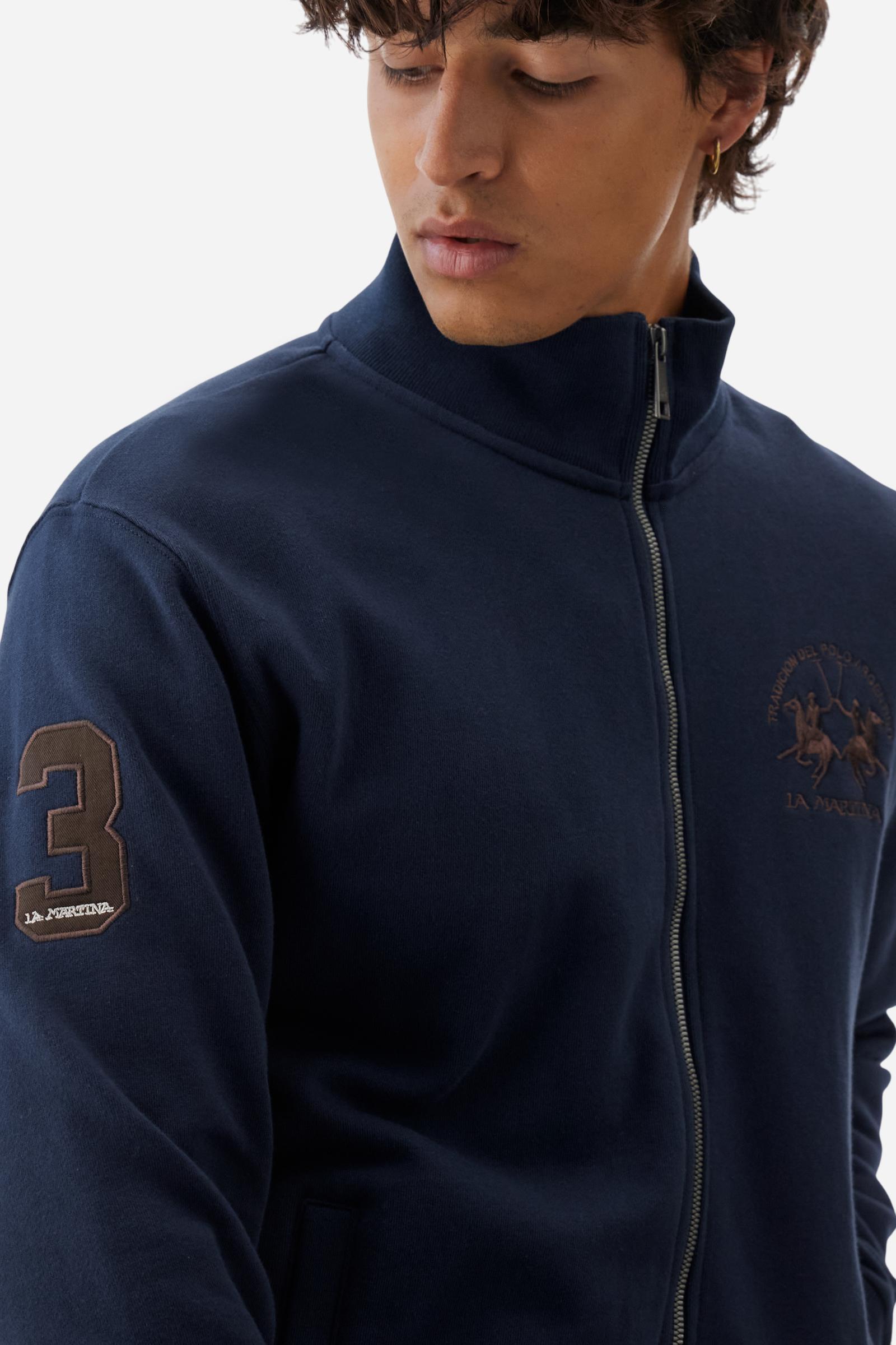 Men's long-sleeved solid colour sweatshirt. It is made of comfortable 100% cotton fleece with a soft-brushed feel. Model with high ribbed neck and front zip opening. Solid colour ribbed cuffs and waistband. The large contrasting brand team logo is embroidered on the chest. A contrasting colour fabric number patch is applied to the right sleeve. The model has a regular fit that offers a comfortable, relaxed silhouette. The model is wearing a size L. - Navy