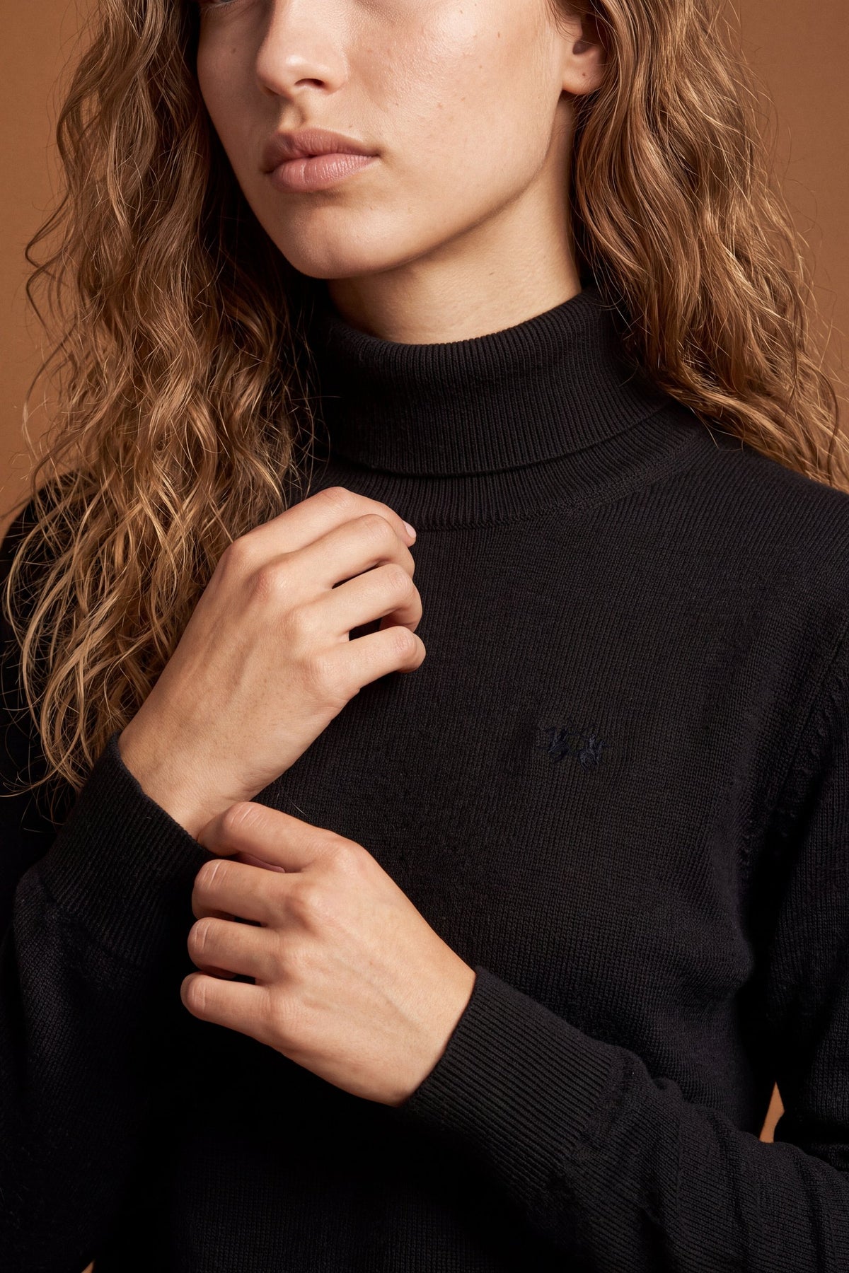 Women's lambswool turtleneck sweater with a soft, ribbed collar, fitted bust, ribbed cuffs and hem, and subtle embroidered logo for a clean, elegant look. - Black