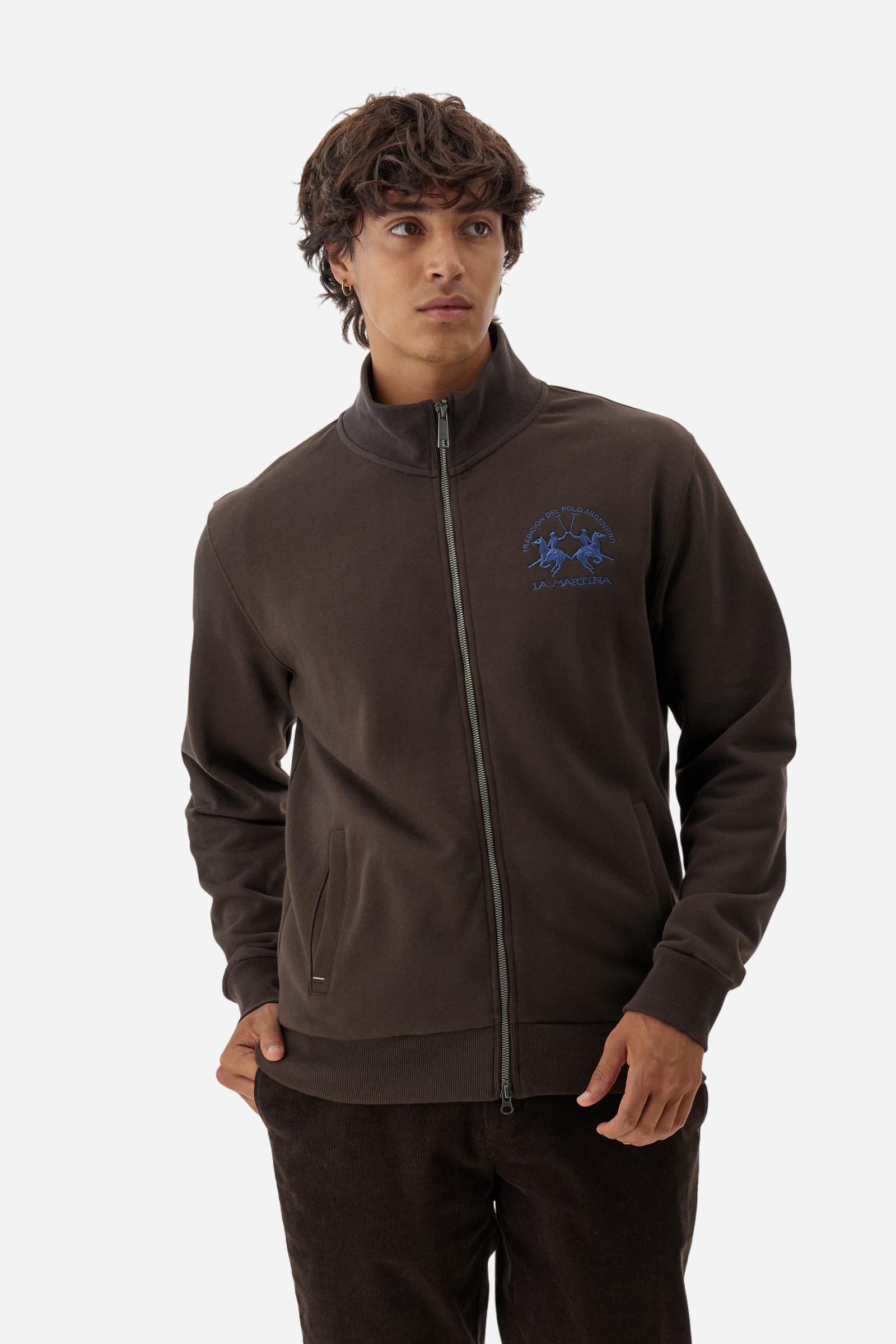Men's long-sleeved solid colour sweatshirt. It is made of comfortable 100% cotton fleece with a soft-brushed feel. Model with high ribbed neck and front zip opening. Solid colour ribbed cuffs and waistband. The large contrasting brand team logo is embroidered on the chest. A contrasting colour fabric number patch is applied to the right sleeve. The model has a regular fit that offers a comfortable, relaxed silhouette. The model is wearing a size L. - Java