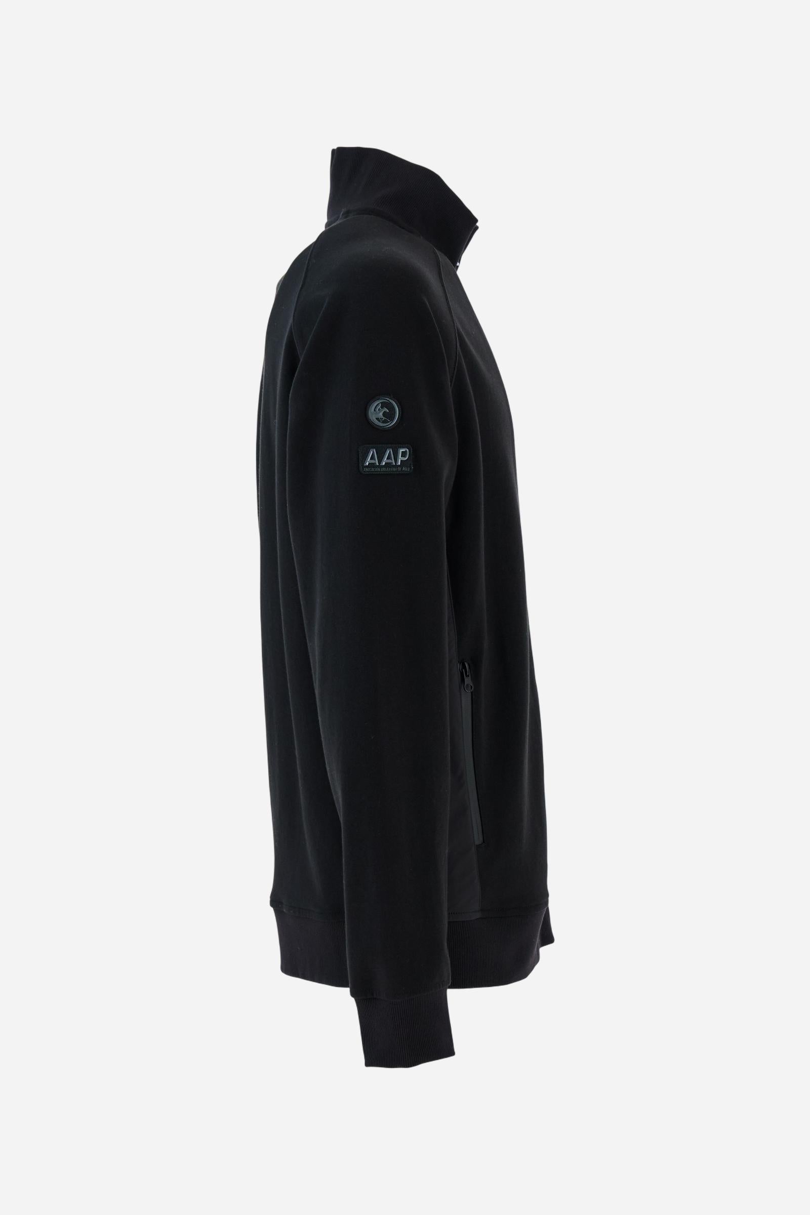 Men's long-sleeved sweatshirt in solid cotton-blend interlock with semi-glossy finish. Features customised front zip, stand-up collar, hem and cuffs in tone-on-tone rib. Large semi-gloss La Martina transfer on the back celebrates the brand's identity, while two patches on the right sleeve recall the Argentine polo association. Regular fit for a practical yet refined style. Model wears size L. - Black