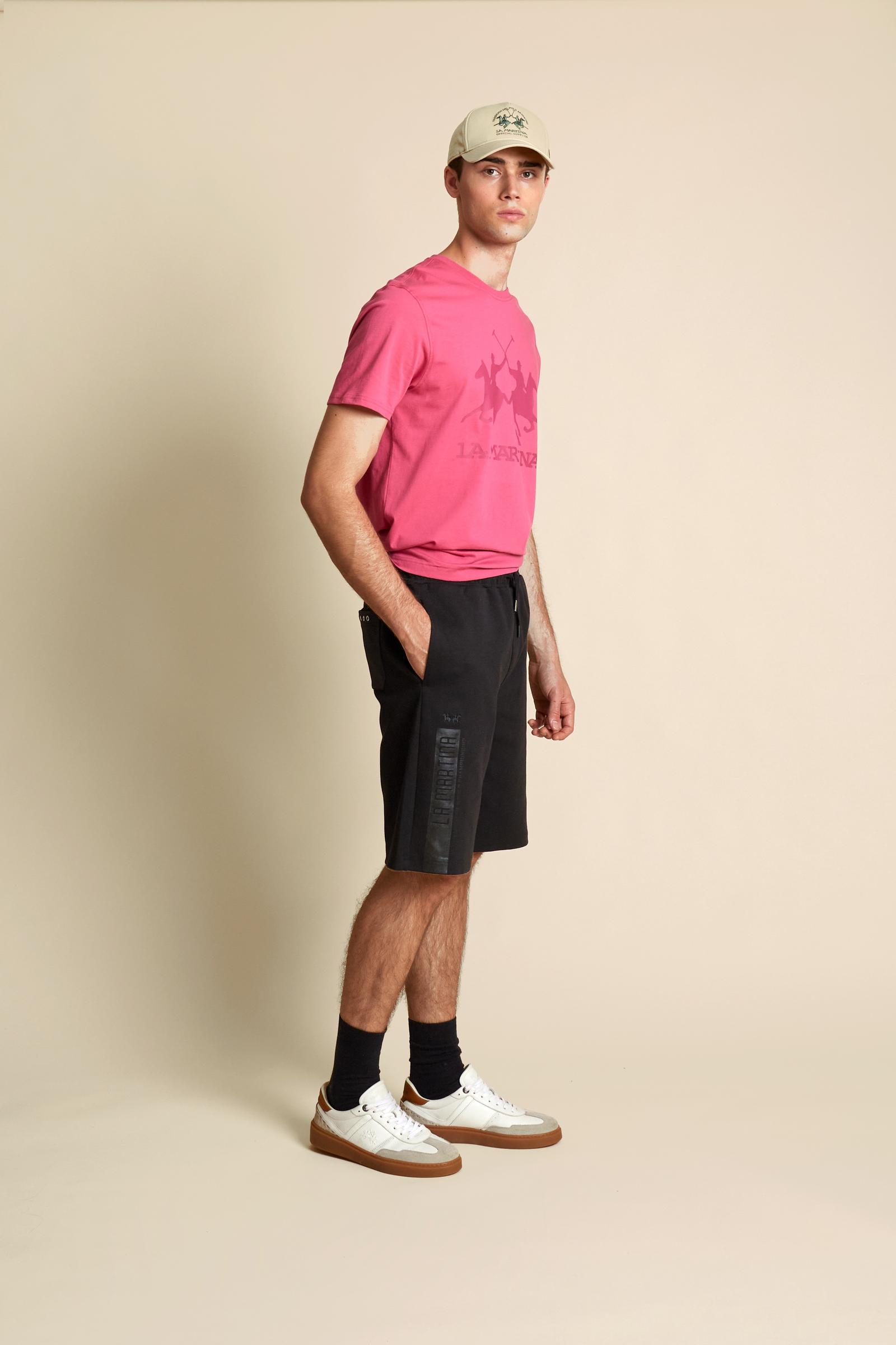 Men’s lightweight interlock bermuda shorts in cotton-blend fabric with a soft technical feel. Modern straight cut above the knee with elastic waistband and external drawstring. Rear patch pocket in contrast fabric with metal stud detail. High-density rubberized side print “La Martina” with Emirates World Championship reference, special edition dedicated to Dubai. The model wears size L. - Black                                                                                                                   