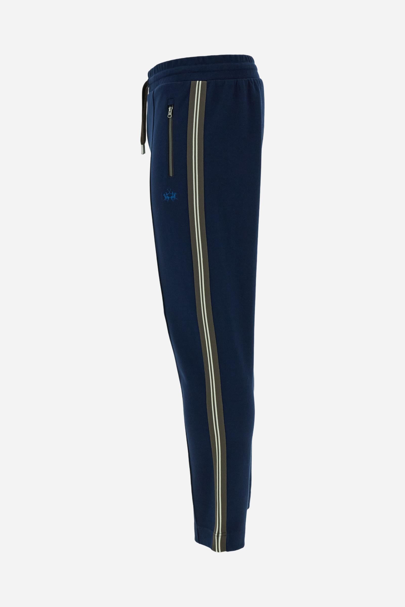 Men’s joggers made of 100% cotton interlock fleece with a bicolor design. Elastic waistband with drawstring for a customizable fit. Two zipped side pockets add practicality, while multicolor striped tape decorates both sides. A vertical crease on the front leg adds refinement to this sporty style. Small embroidered logo in contrast under the left pocket. Regular straight-leg fit for a classic, comfortable silhouette. Model wears size L. - Navy