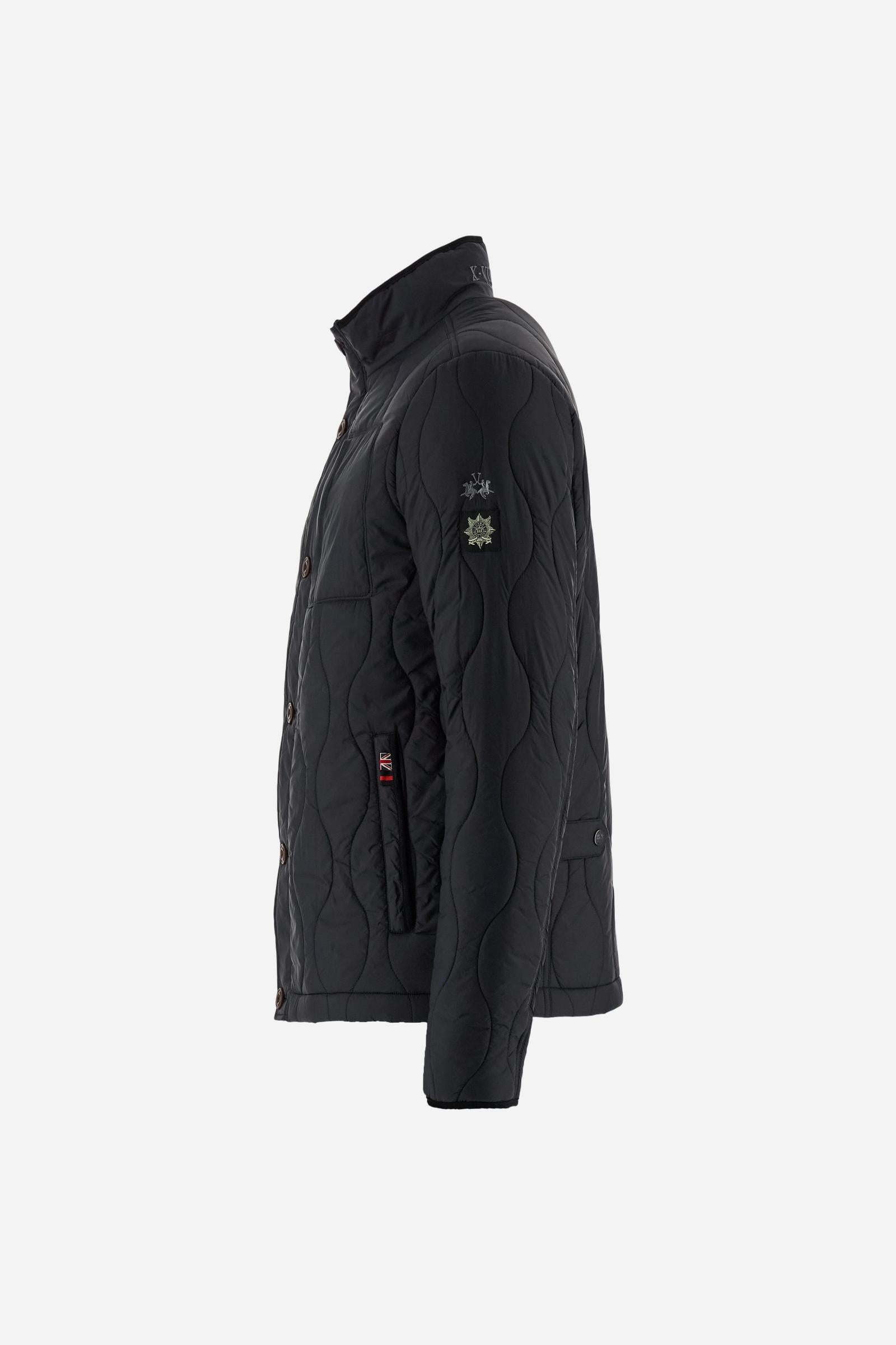 Men’s quilted nylon husky jacket with high collar. Front closure with customized zip and large faux-leather buttons. Interior lined with striped bicolor polyester. Contrast details on the inside (pockets, profiles, back-neck tab). Clean design with chest pocket closed by zip and vertical side pockets. Adjustable back straps with metal snap buttons. Logo patches on the sleeves and multicolor embroidered lettering on the outer collar. Part of the Guards capsule. Regular fit. Model wears size L. - Black