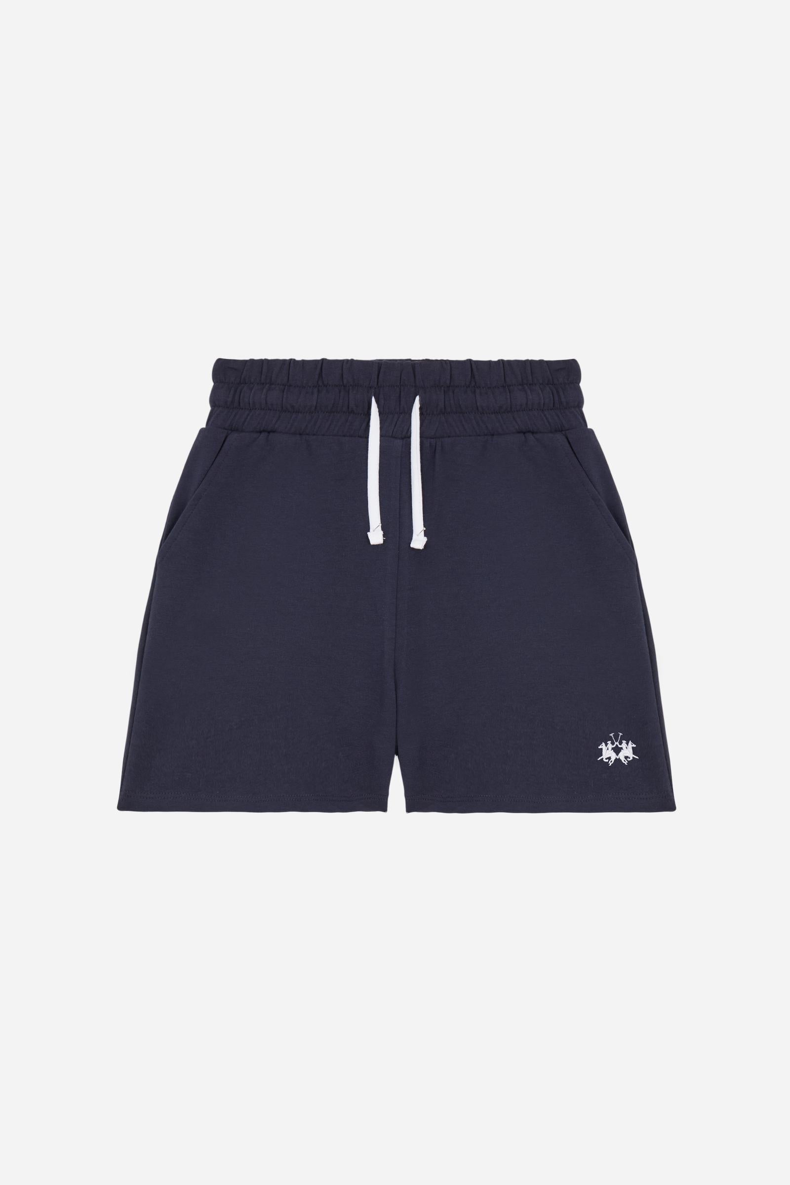 Bermuda shorts for girls made from soft 100% cotton fleece in a solid colour. The style features a regular fit, short leg and elasticated waist with adjustable drawstring. The small contrast embroidered brand logo on the left leg adds a discreet and distinctive detail. A comfortable, versatile garment, ideal for casual and sporty looks. - Navy