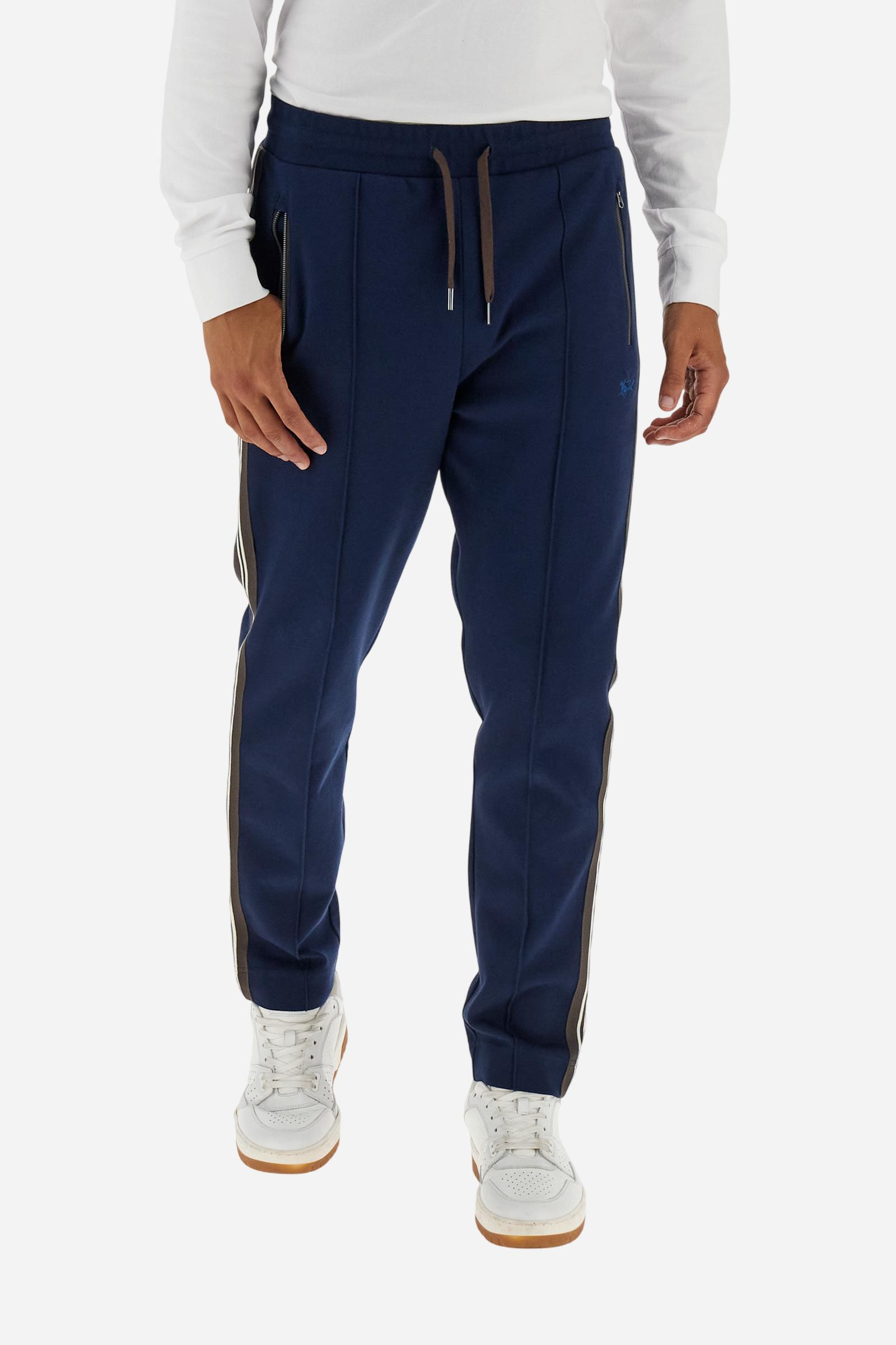 Men’s joggers made of 100% cotton interlock fleece with a bicolor design. Elastic waistband with drawstring for a customizable fit. Two zipped side pockets add practicality, while multicolor striped tape decorates both sides. A vertical crease on the front leg adds refinement to this sporty style. Small embroidered logo in contrast under the left pocket. Regular straight-leg fit for a classic, comfortable silhouette. Model wears size L. - Navy