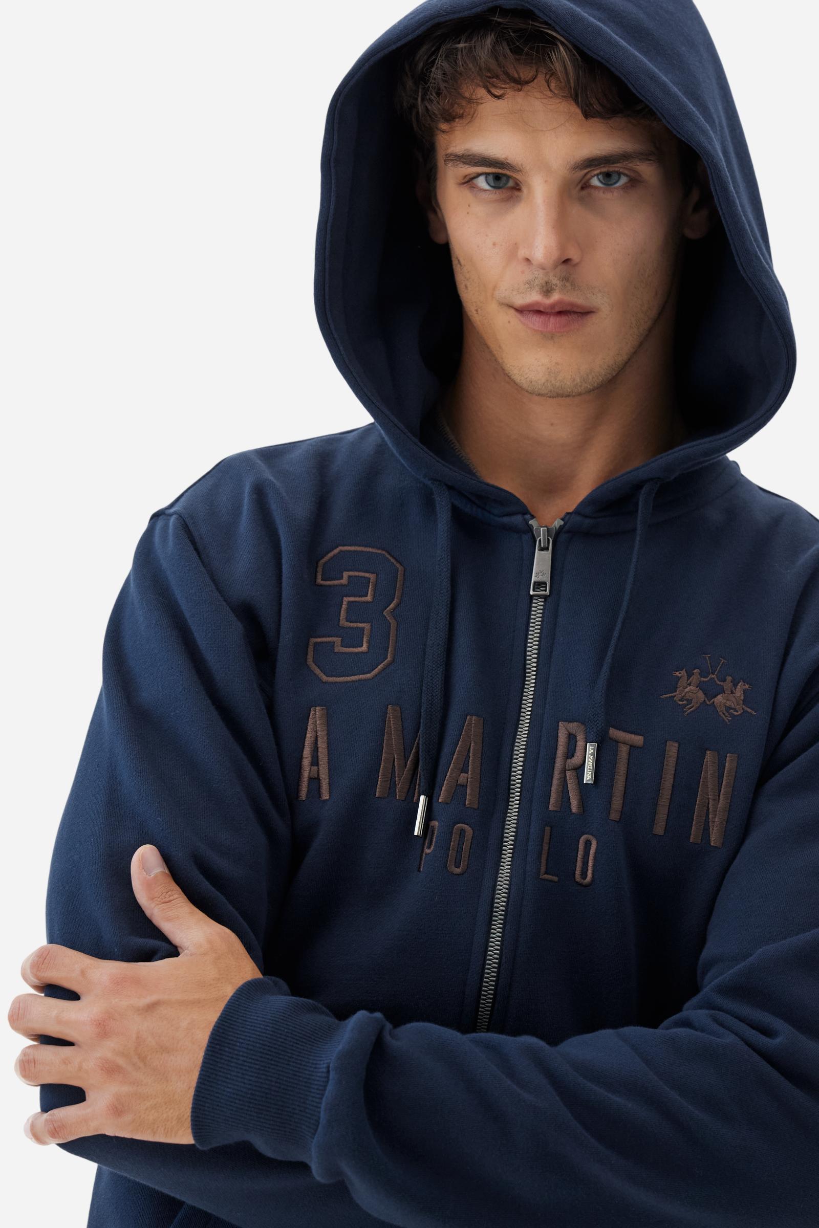 Men's long-sleeved hoodie in solid colour, made from soft 100% cotton fleece with a velvety touch. The model features a customised front zip and an adjustable hood with drawstring. Hem and cuffs in tone-on-tone rib. Iconic brand graphics stand out on the chest, embroidered with numbers and lettering. Regular fit ensuring comfort and freedom of movement. Model wears size L. - Navy
