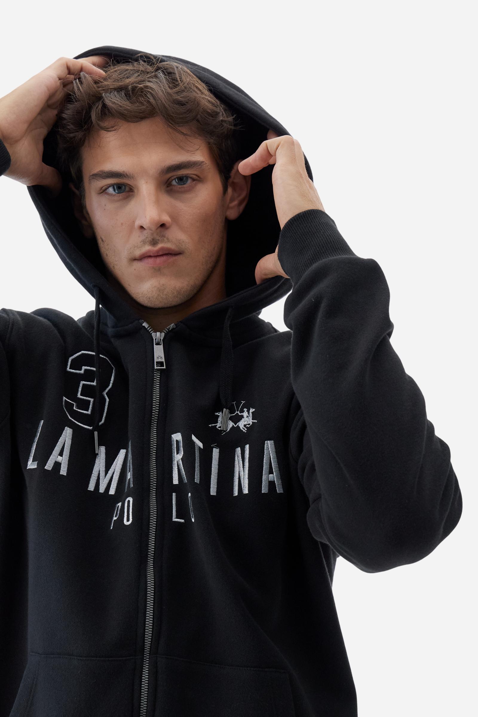 Men's long-sleeved hoodie in solid colour, made from soft 100% cotton fleece with a velvety touch. The model features a customised front zip and an adjustable hood with drawstring. Hem and cuffs in tone-on-tone rib. Iconic brand graphics stand out on the chest, embroidered with numbers and lettering. Regular fit ensuring comfort and freedom of movement. Model wears size L. - Black