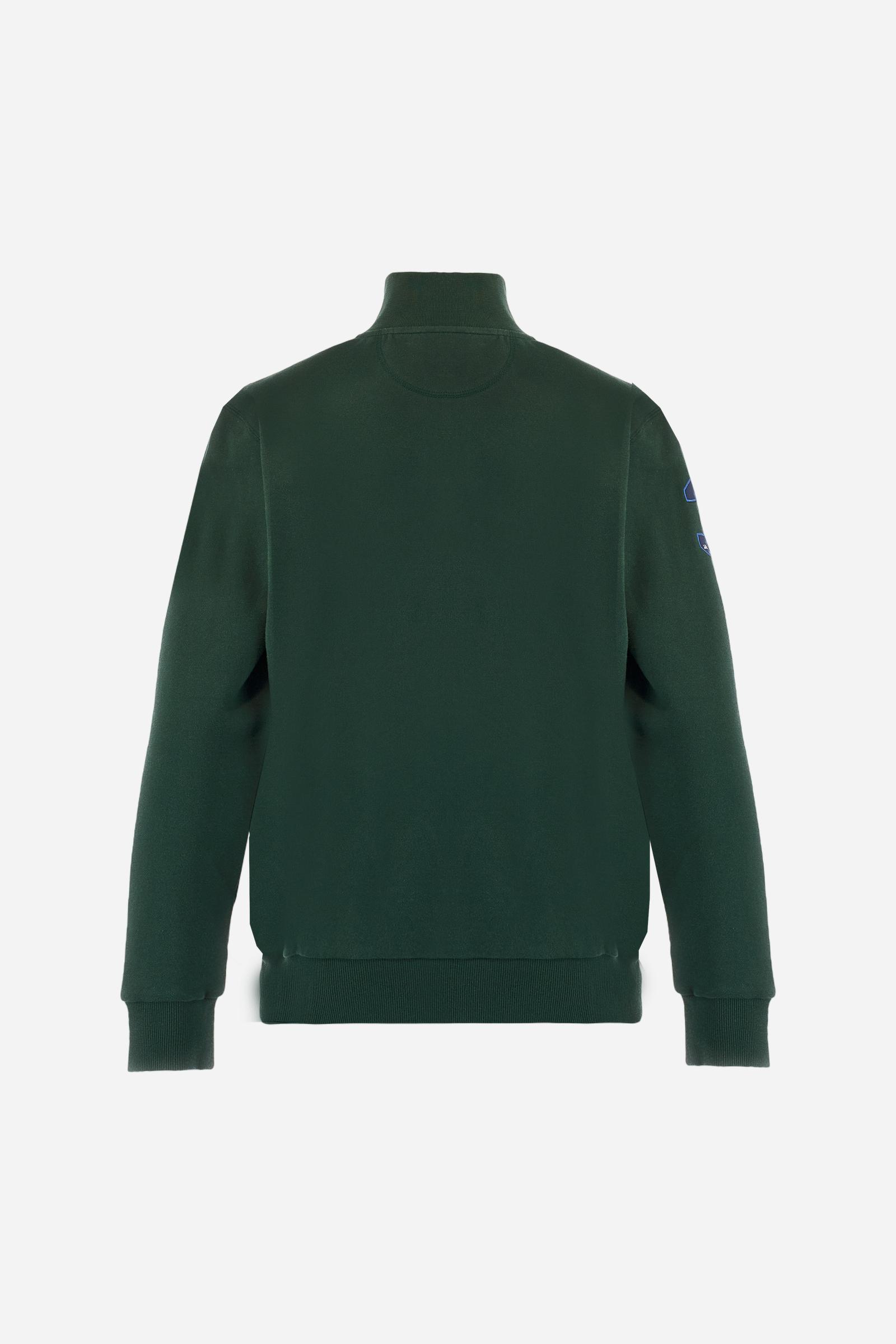 Men's long-sleeved solid colour sweatshirt. It is made of comfortable 100% cotton fleece with a soft-brushed feel. Model with high ribbed neck and front zip opening. Solid colour ribbed cuffs and waistband. The large contrasting brand team logo is embroidered on the chest. A contrasting colour fabric number patch is applied to the right sleeve. The model has a regular fit that offers a comfortable, relaxed silhouette. The model is wearing a size L. - Sycamore