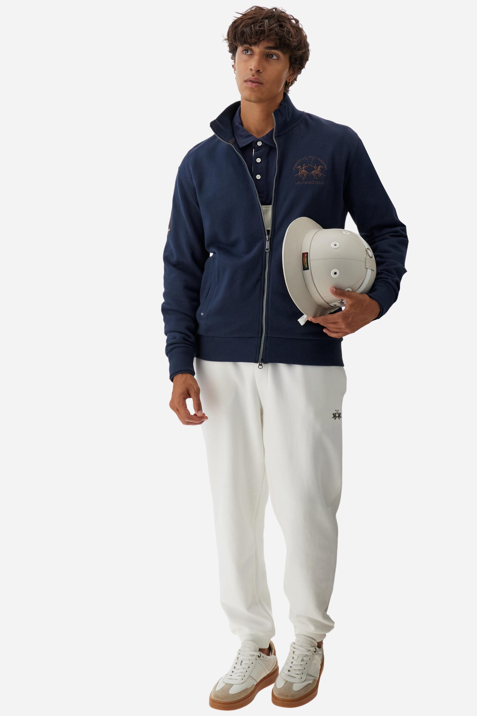 Men's long-sleeved solid colour sweatshirt. It is made of comfortable 100% cotton fleece with a soft-brushed feel. Model with high ribbed neck and front zip opening. Solid colour ribbed cuffs and waistband. The large contrasting brand team logo is embroidered on the chest. A contrasting colour fabric number patch is applied to the right sleeve. The model has a regular fit that offers a comfortable, relaxed silhouette. The model is wearing a size L. - Navy