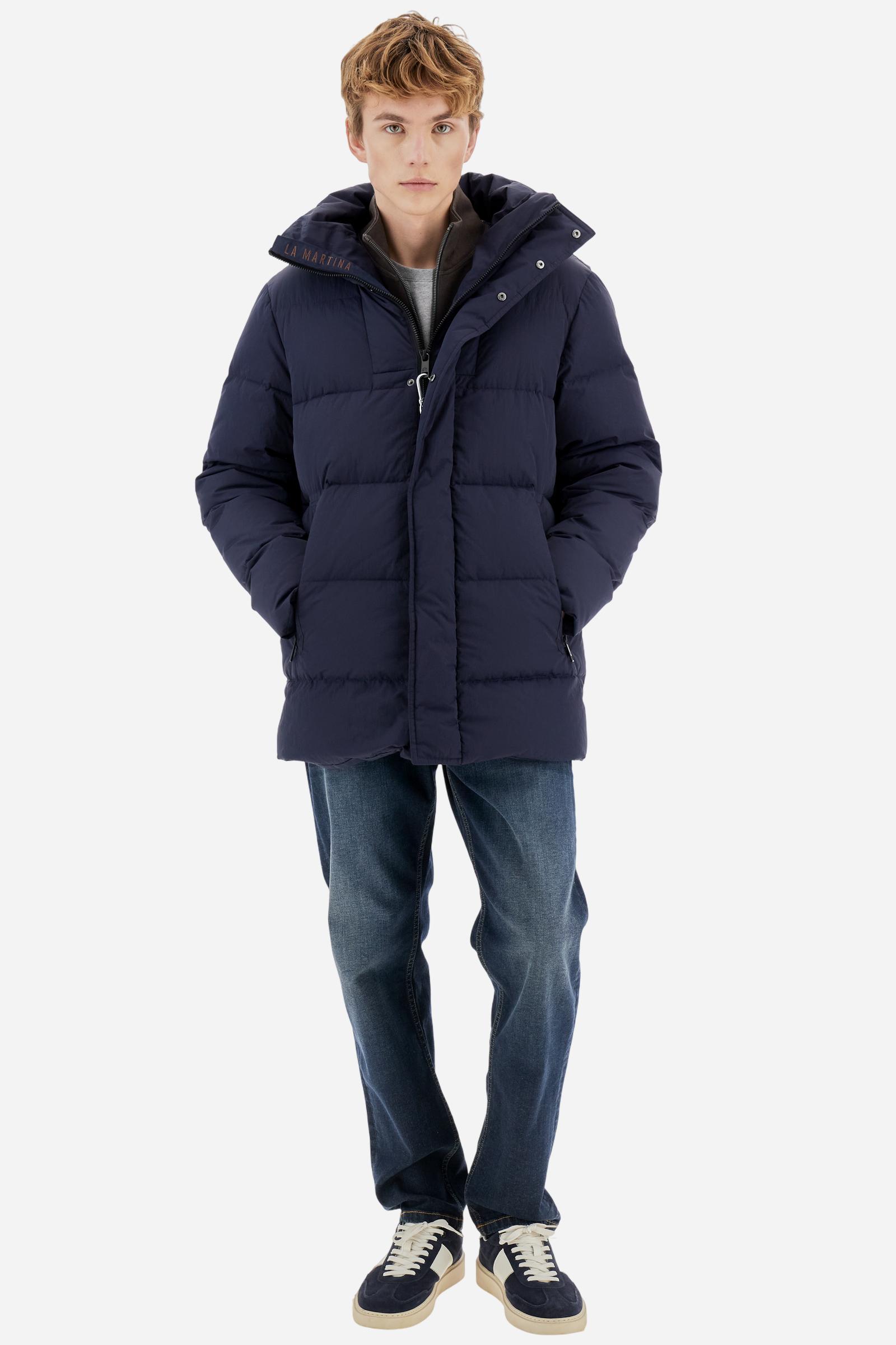 Men's long down jacket in solid crinkled nylon with detachable hood. Filled with down and fully lined in contrast, designed to provide warmth and lightness. The removable hood is adjustable with elastic drawstrings. Double zip closure with exclusive carabiner puller. Inside placket features contrasting La Martina embroidery, while a logo patch on the left sleeve completes the garment. Designed to combine urban functionality with technical performance. Regular, comfortable fit. Model wears size L. - Navy