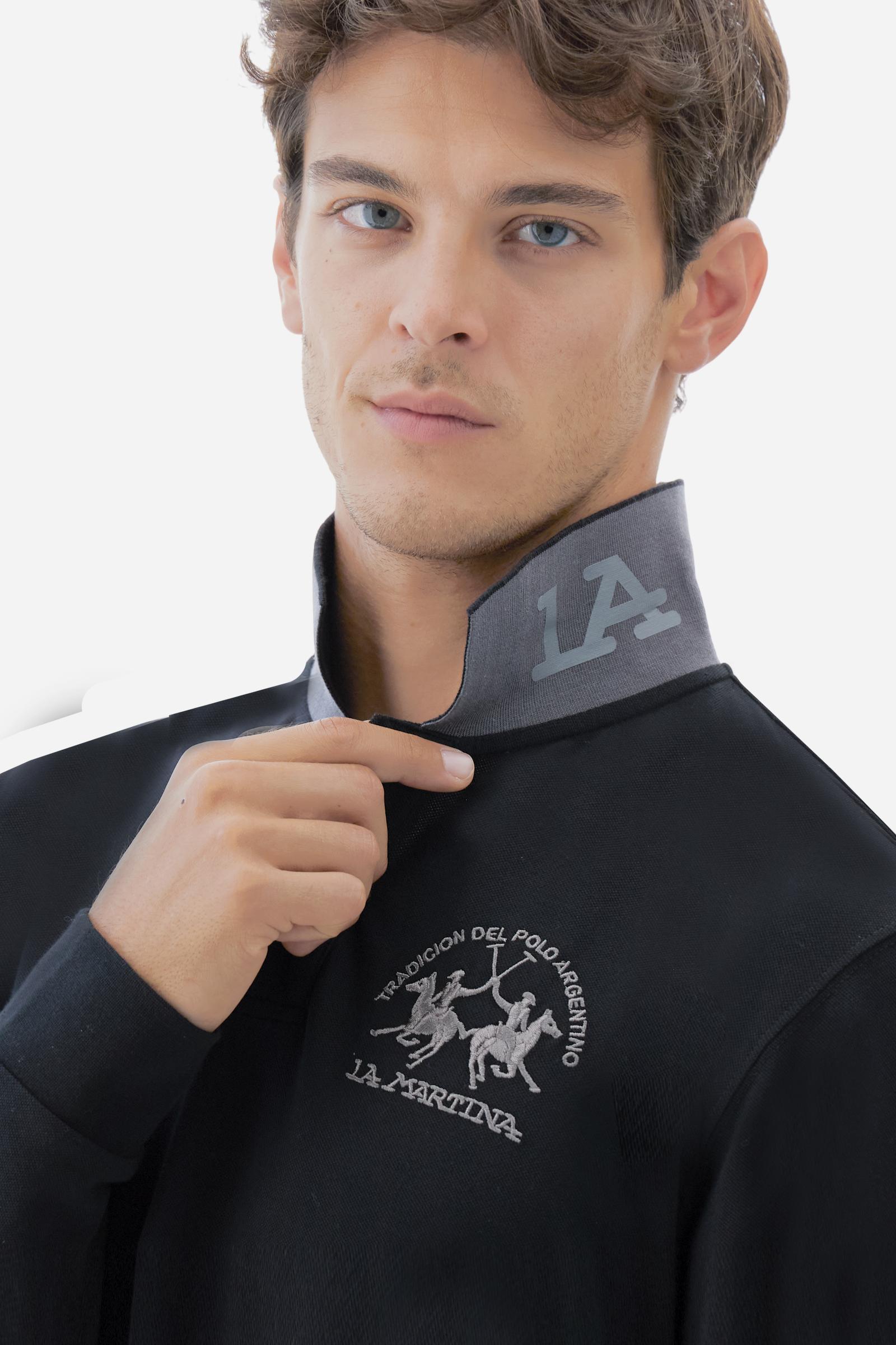 Men's long-sleeved solid colour polo shirt. Made of high-quality stretch Piqué. The collar and cuffs are in solid colour ribbing. The undercollar features a print of the iconic La Martina lettering in a contrasting colour. Featuring a logo embroidered on the chest in a contrasting colour. On the back at the bottom, the guarantee label typical of the brand's iconic models is applied. Regular fit. The model is wearing a size L. - Black