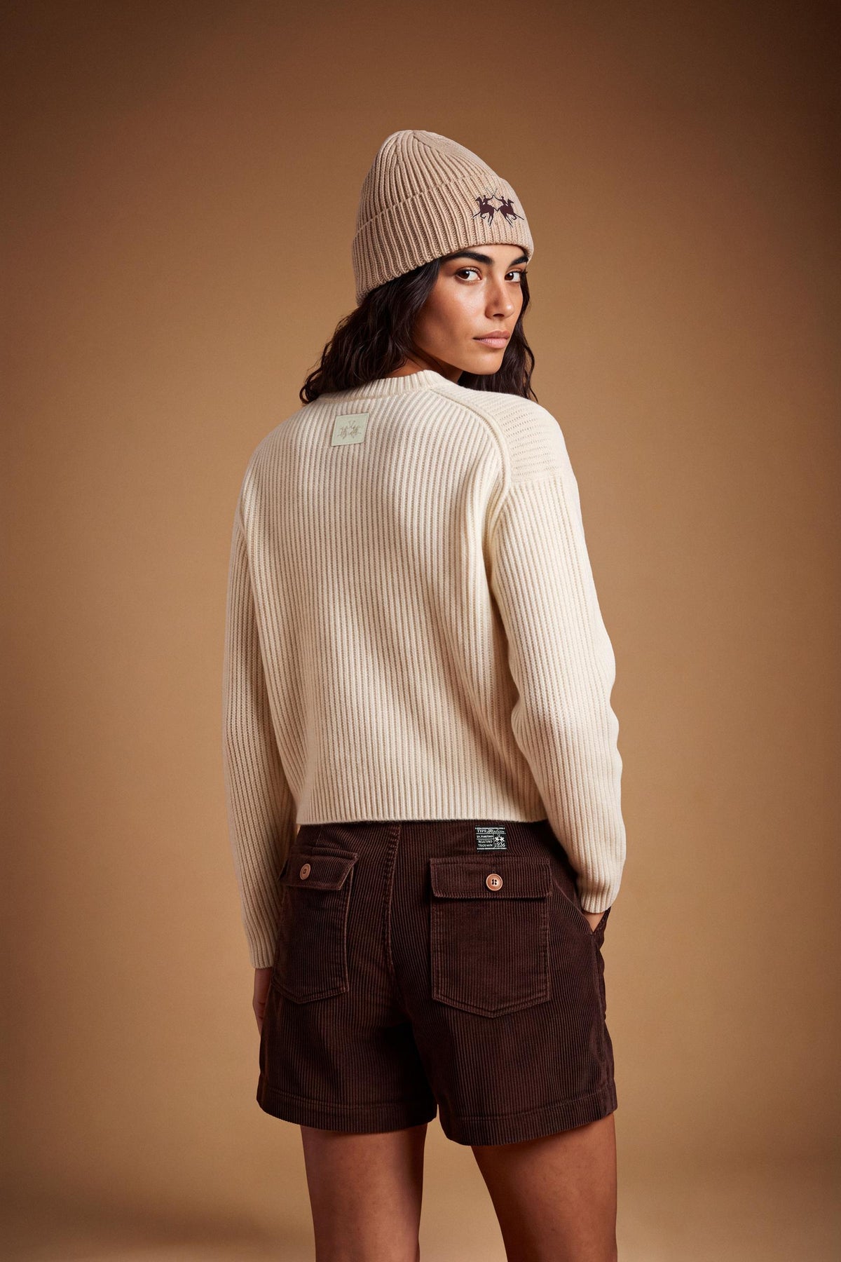Soft lambswool women's sweater with vertical ribbed knit, relaxed fit, dropped shoulders, cropped length, and a subtle embroidered logo on the back neckline. - Antique White