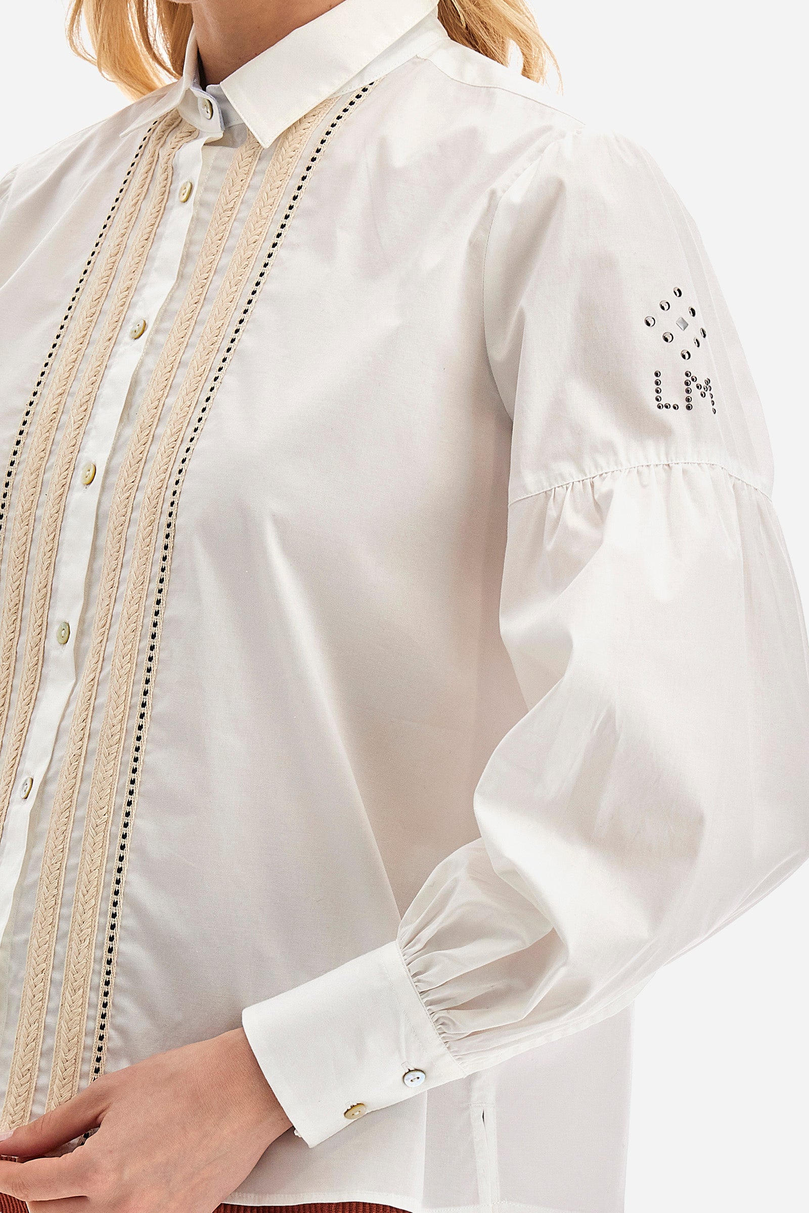 The Argentina women's shirt is made of solid-coloured stretch cotton, with an elegant regular fit. The design features a refined classic collar and button fastening with cable and openwork trims, giving the shirt a distinctive edge. The long sleeves, adorned at the top with a balloon effect, give the shirt a delicate and romantic look. Finally, the LM logo applied the sleeve completes the garment with a sophisticated and contemporary aesthetic. The model is 174 cm tall and wears a size 2. - Optic White