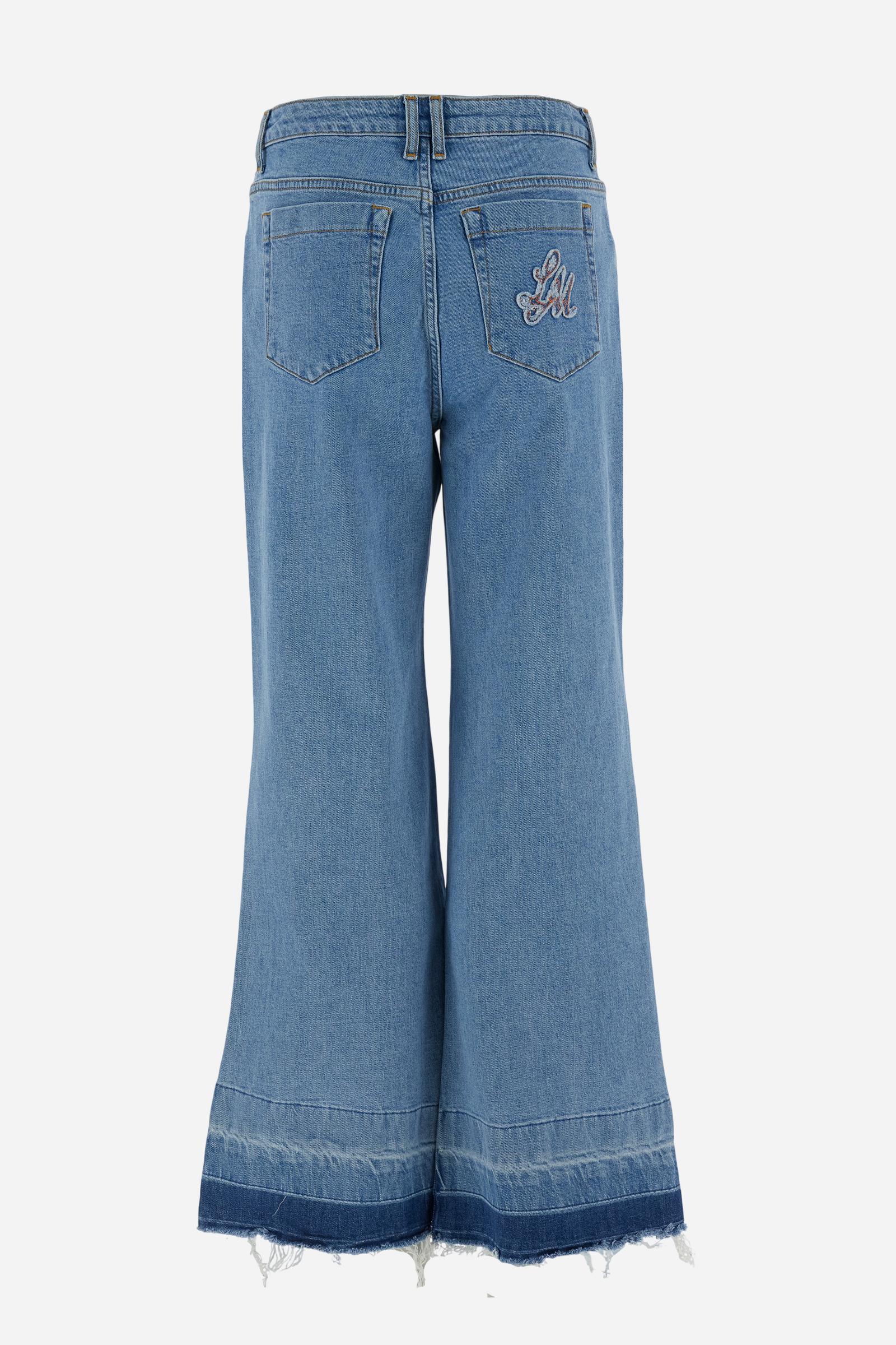 Women’s denim jeans in light-medium wash with a five-pocket style, wide leg, and raw-cut hem. Features logo details on pockets and leather patch. - Medium Indigo Denim