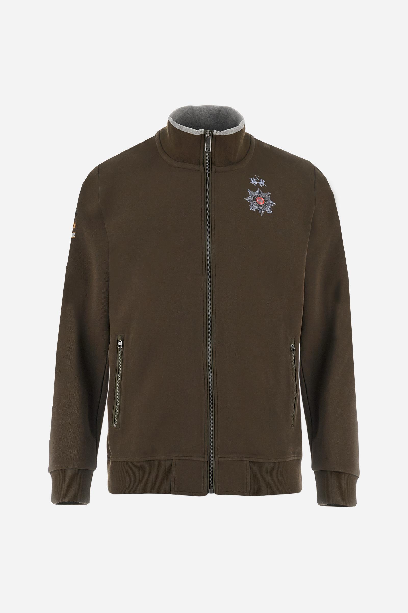 Men's long-sleeved, full-zip solid colour sweatshirt. Made of stretch cotton-blend piqué. Design with front opening fastened by a zip, high collar in two-tone ribbing. Solid colour ribbed cuffs and waistband. The small brand logo and Guards crest are embroidered in multi-coloured thread on the chest. On the right sleeve, there is another embroidery of a crest inspired by the British royal household. The regular fit silhouette is practical for everyday wear. The model is wearing a size L. - Java