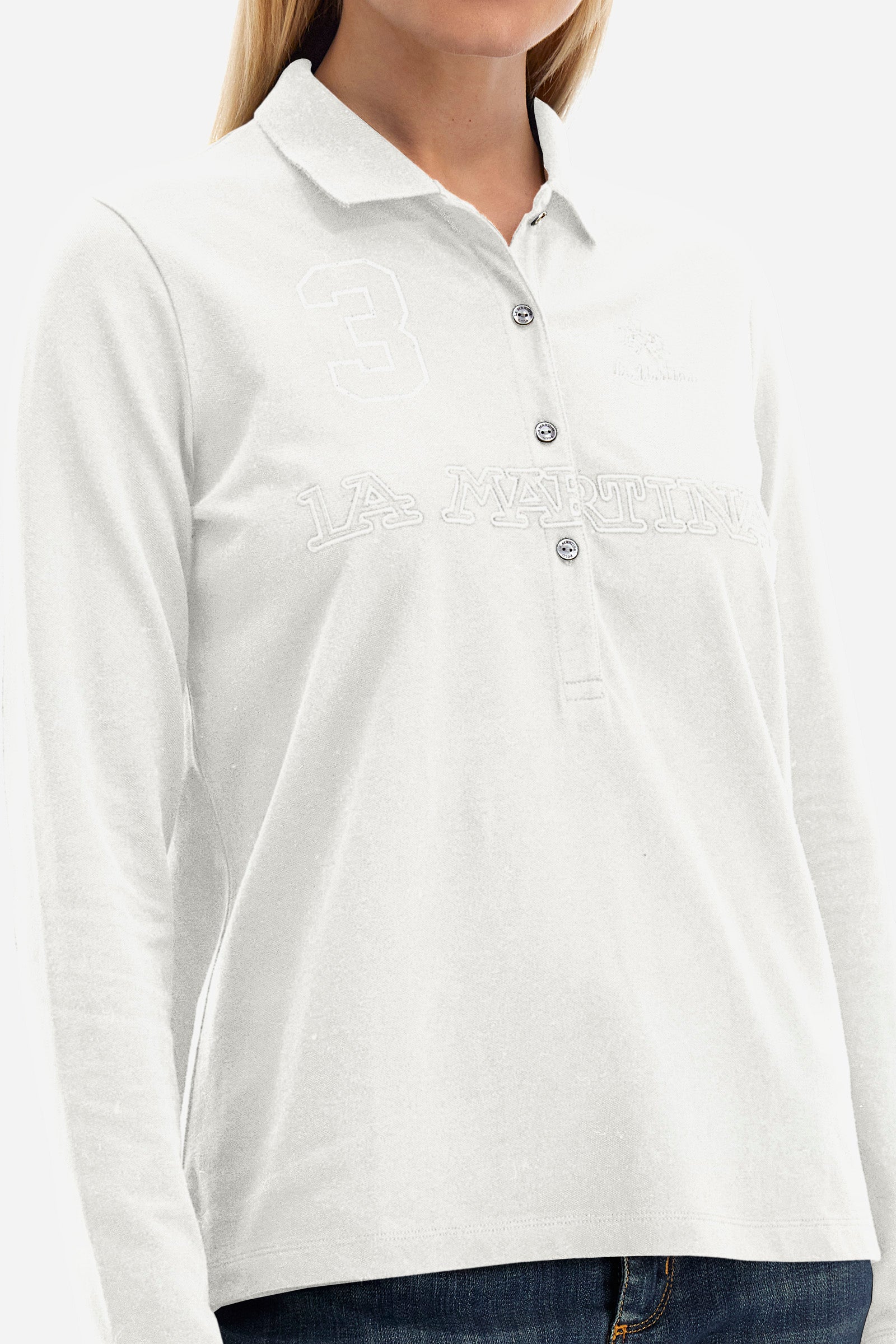 This women's polo shirt from the Timeless line is made of stretch cotton and has a regular fit. Available in a wide range of colours, it is perfect for those looking for a simple but quality garment. The solid colour and the embossed print of the La Martina logo on the front, together with the number 3, make it an elegant and unique garment. The classic 4-button collar completes the ideal look for a casual or sporty outfit. The model is 174 cm tall and wears a size 2. - Blanc de Blanc