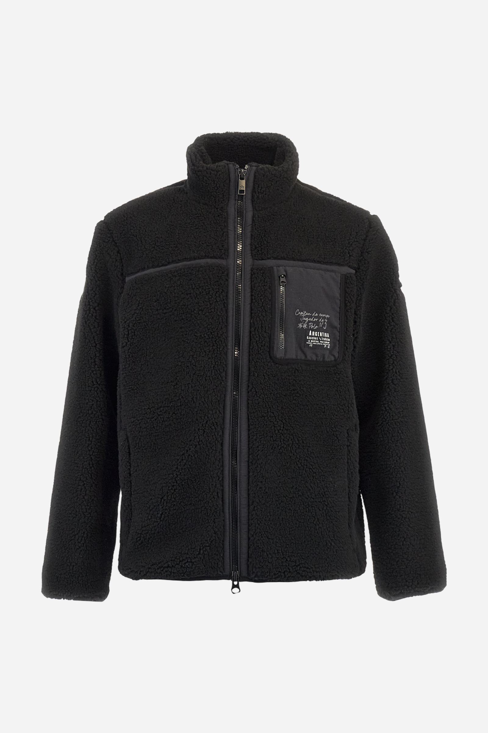 Men’s teddy jacket in 100% polyester with high collar and full lining. Front closure with customized tone-on-tone zip. Finished with matte nylon trims on seams and edges, also used for the zipped chest pocket. High collar offers extra wind protection. Patches inspired by Argentina and Jugador de Polo on sleeve and chest pocket. Regular, straight fit. Model wears size L. - Black