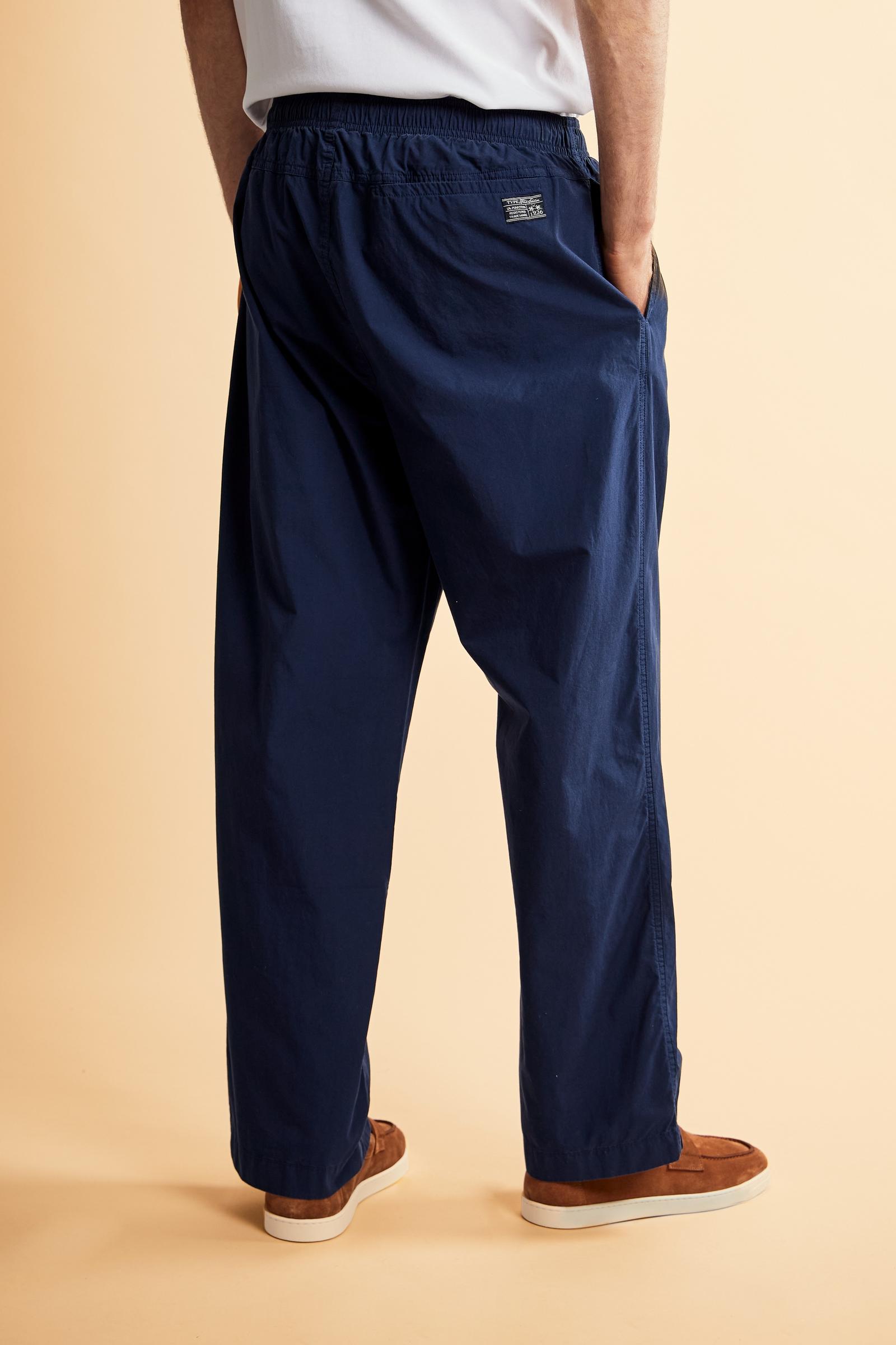 Men’s long trousers made from 100% cotton poplin in a solid color, a lightweight yet durable fabric with a soft hand, ideal for warmer seasons. The model features a straight and relaxed cut with an elasticated waistband and adjustable drawstring for maximum comfort and adaptability. Side seam pockets provide practicality, while the back welt pocket is integrated into the yoke seam and finished with visible double stitching. The distinctive detail is the Black Edition label applied above the back pocket, com