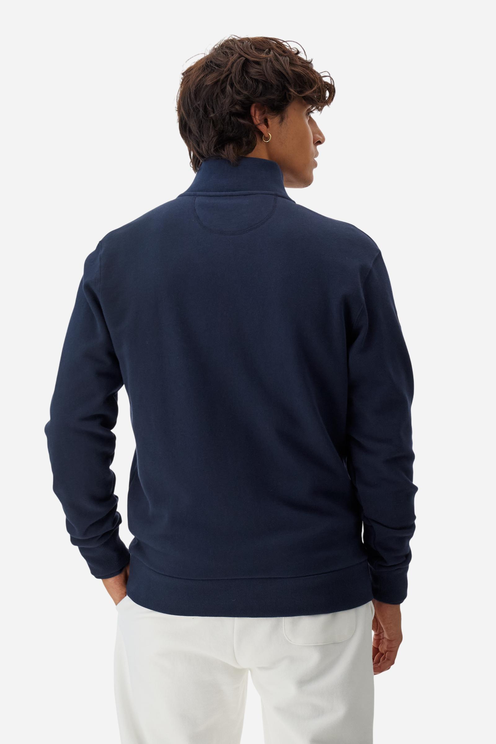 Men's long-sleeved solid colour sweatshirt. It is made of comfortable 100% cotton fleece with a soft-brushed feel. Model with high ribbed neck and front zip opening. Solid colour ribbed cuffs and waistband. The large contrasting brand team logo is embroidered on the chest. A contrasting colour fabric number patch is applied to the right sleeve. The model has a regular fit that offers a comfortable, relaxed silhouette. The model is wearing a size L. - Navy