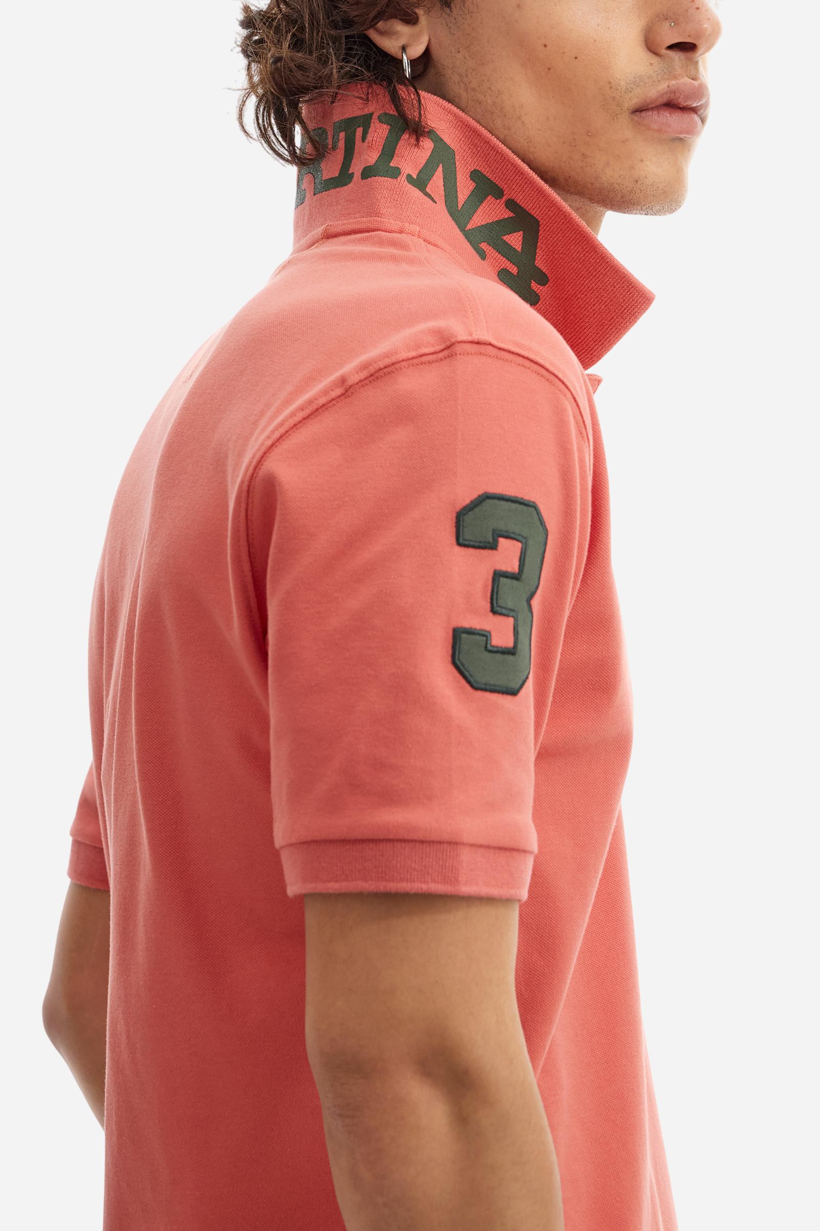 Men's plain short-sleeved polo shirt made from stretch piqué. Two-button fastening. The collar and cuffs are made from tone-on-tone ribbed fabric. A contrasting fabric patch depicting the number 3 is appliquéd on the right sleeve. The logo is embroidered on the left side of the chest in contrasting thread. Under the collar, there is a large contrasting print of the La Martina lettering. Regular fit. The model is wearing a size L. - Acai
