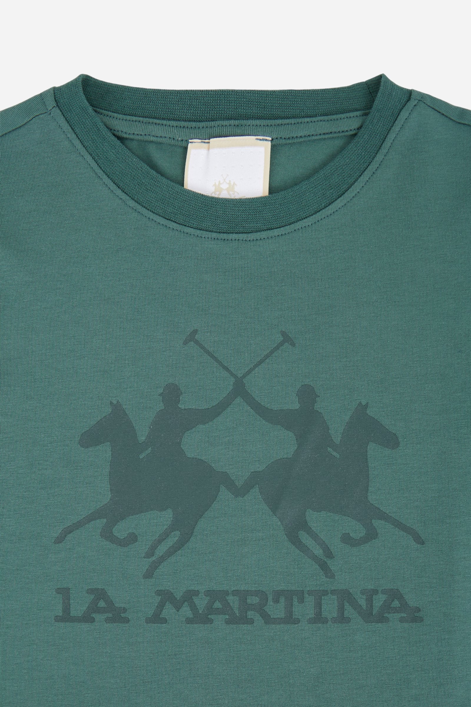 Short-sleeved T-shirt for girls made from soft 100% cotton jersey in a solid colour. The style features a regular fit and tonal ribbed crew neck. The maxi front print, featuring the iconic crossed polo players logo and La Martina lettering, enhances the garment with a sporty and recognisable style. - Pineneedle