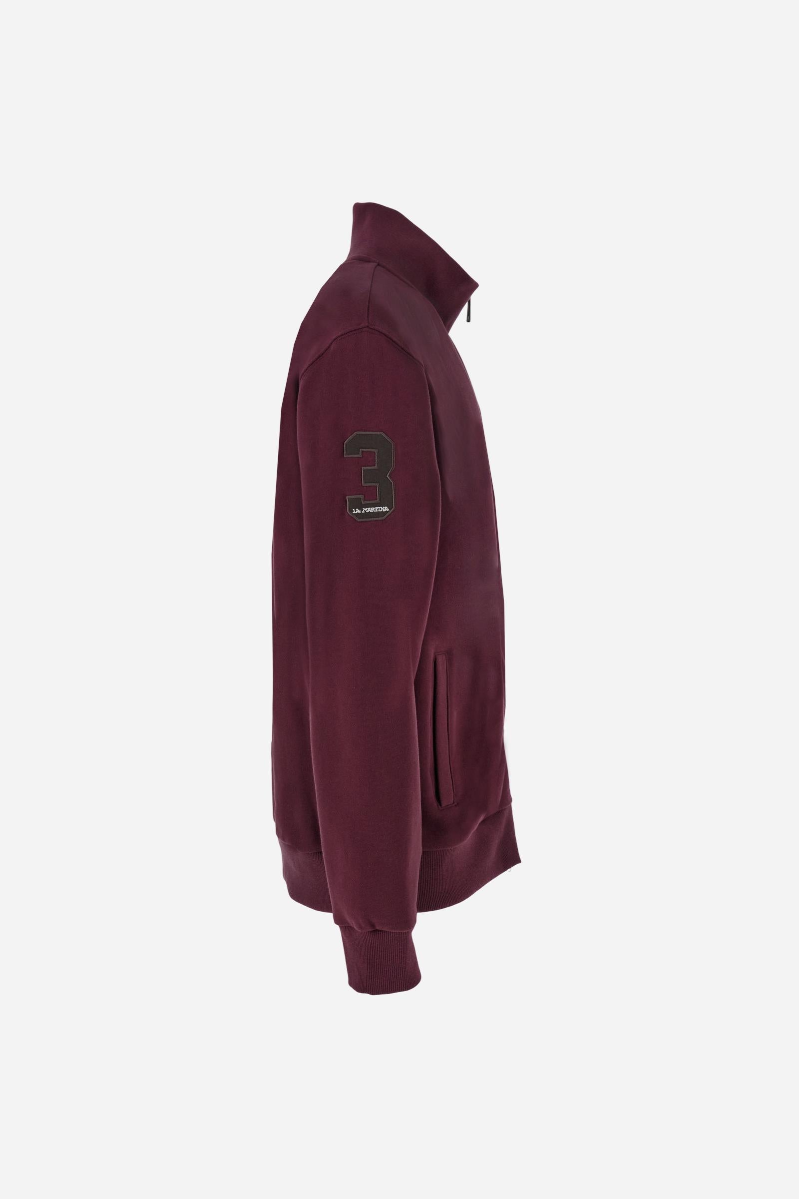 Men's long-sleeved solid colour sweatshirt. It is made of comfortable 100% cotton fleece with a soft-brushed feel. Model with high ribbed neck and front zip opening. Solid colour ribbed cuffs and waistband. The large contrasting brand team logo is embroidered on the chest. A contrasting colour fabric number patch is applied to the right sleeve. The model has a regular fit that offers a comfortable, relaxed silhouette. The model is wearing a size L. - Port Royale