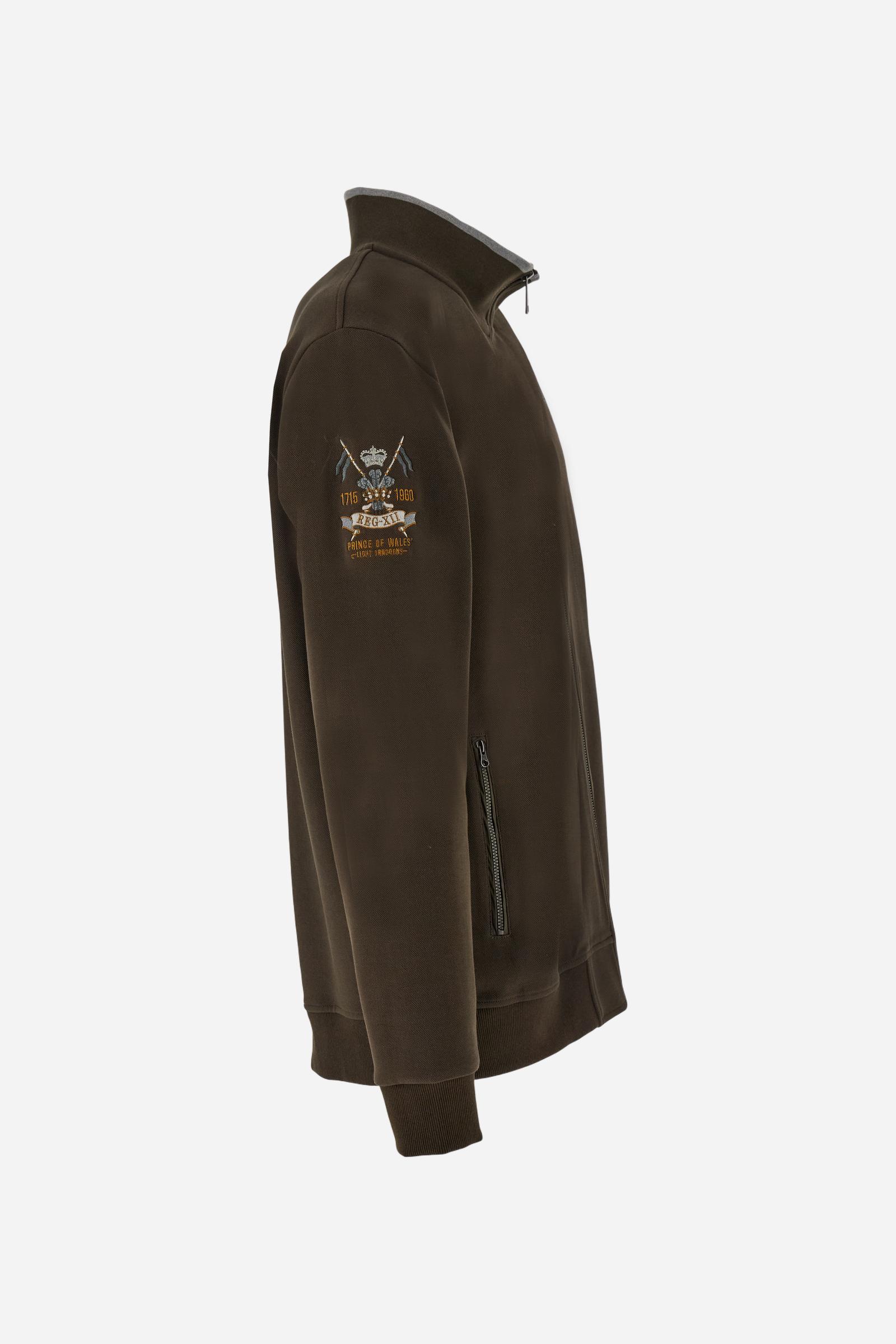 Men's long-sleeved, full-zip solid colour sweatshirt. Made of stretch cotton-blend piqué. Design with front opening fastened by a zip, high collar in two-tone ribbing. Solid colour ribbed cuffs and waistband. The small brand logo and Guards crest are embroidered in multi-coloured thread on the chest. On the right sleeve, there is another embroidery of a crest inspired by the British royal household. The regular fit silhouette is practical for everyday wear. The model is wearing a size L. - Java