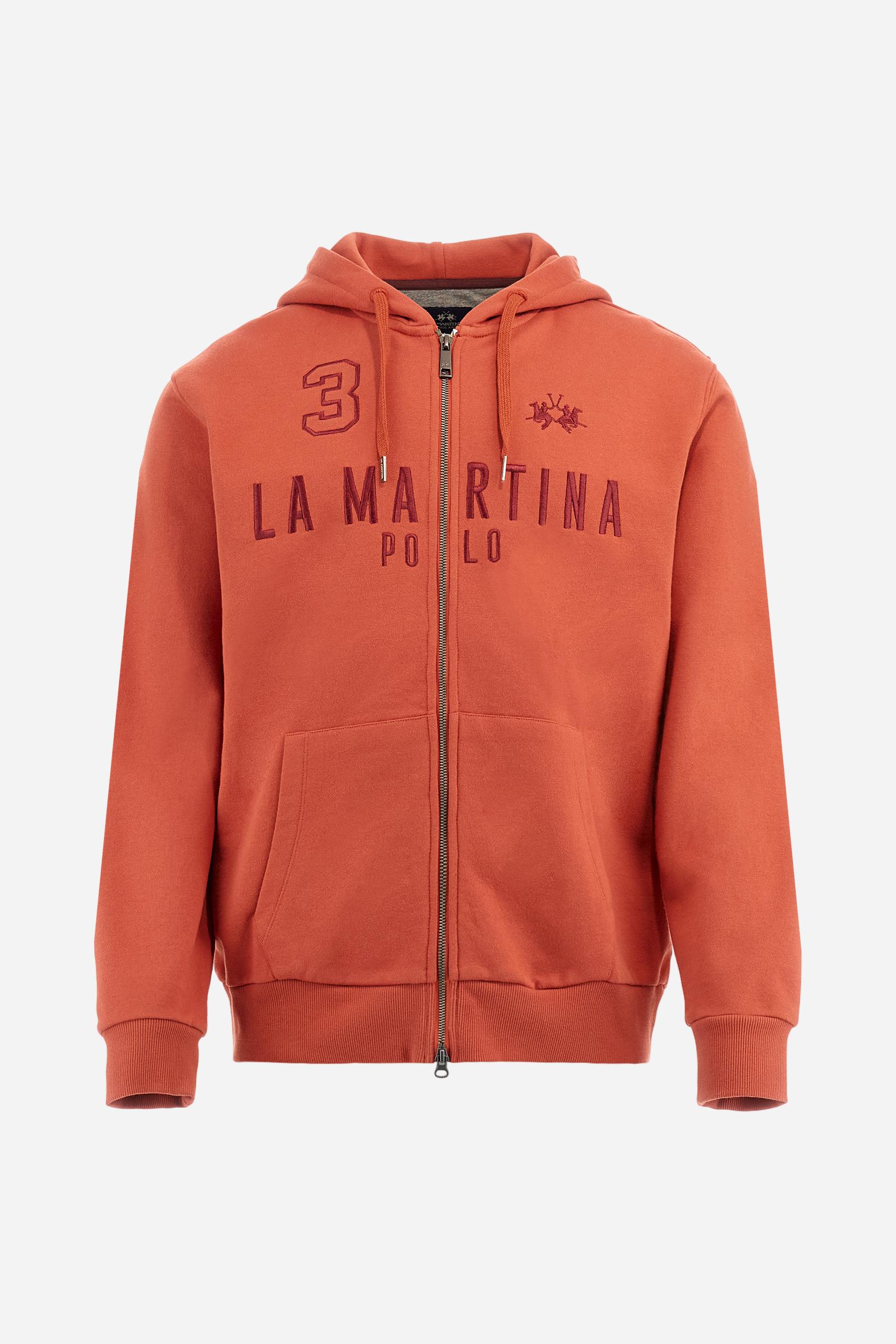 Men's long-sleeved hoodie in solid colour, made from soft 100% cotton fleece with a velvety touch. The model features a customised front zip and an adjustable hood with drawstring. Hem and cuffs in tone-on-tone rib. Iconic brand graphics stand out on the chest, embroidered with numbers and lettering. Regular fit ensuring comfort and freedom of movement. Model wears size L. - Burnt Ochre