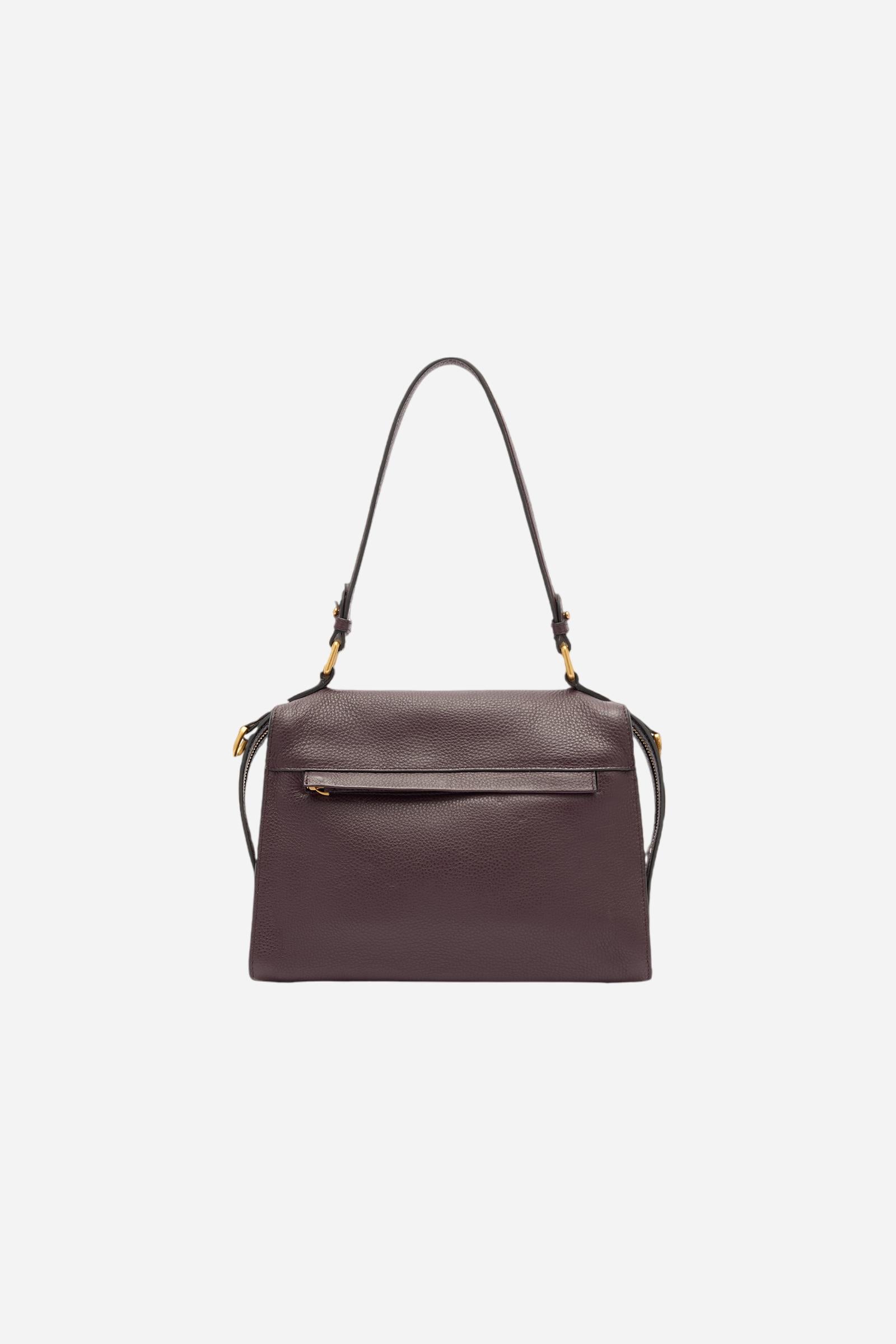 Compact shoulder bag made of high-quality full-grain leather. The double side zip with long leather pullers creates both functional and decorative detail. The slightly trapeze silhouette and the gold metal logo plaque define its distinctive and elegant character. Dimensions:28 x 22 x 12 - WINE