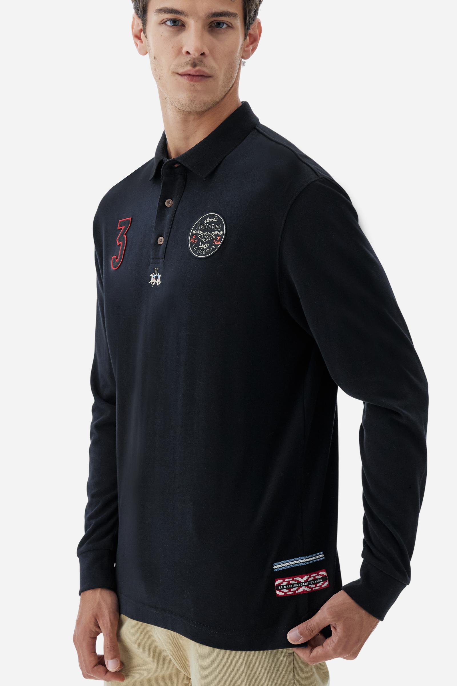 Long-sleeve polo shirt crafted from 100% high-quality cotton jersey. The velvety fabric offers a warm, cozy feel, perfect for cooler seasons. Ribbed collar and cuffs in matching tone, with a three-button personalized placket. A small multicolor embroidered logo sits below the opening, while tonal patches in different shapes and textures, inspired by Argentine culture and Gaucho tradition, decorate the chest and back. Classic regular fit. Model wears size L. - Black