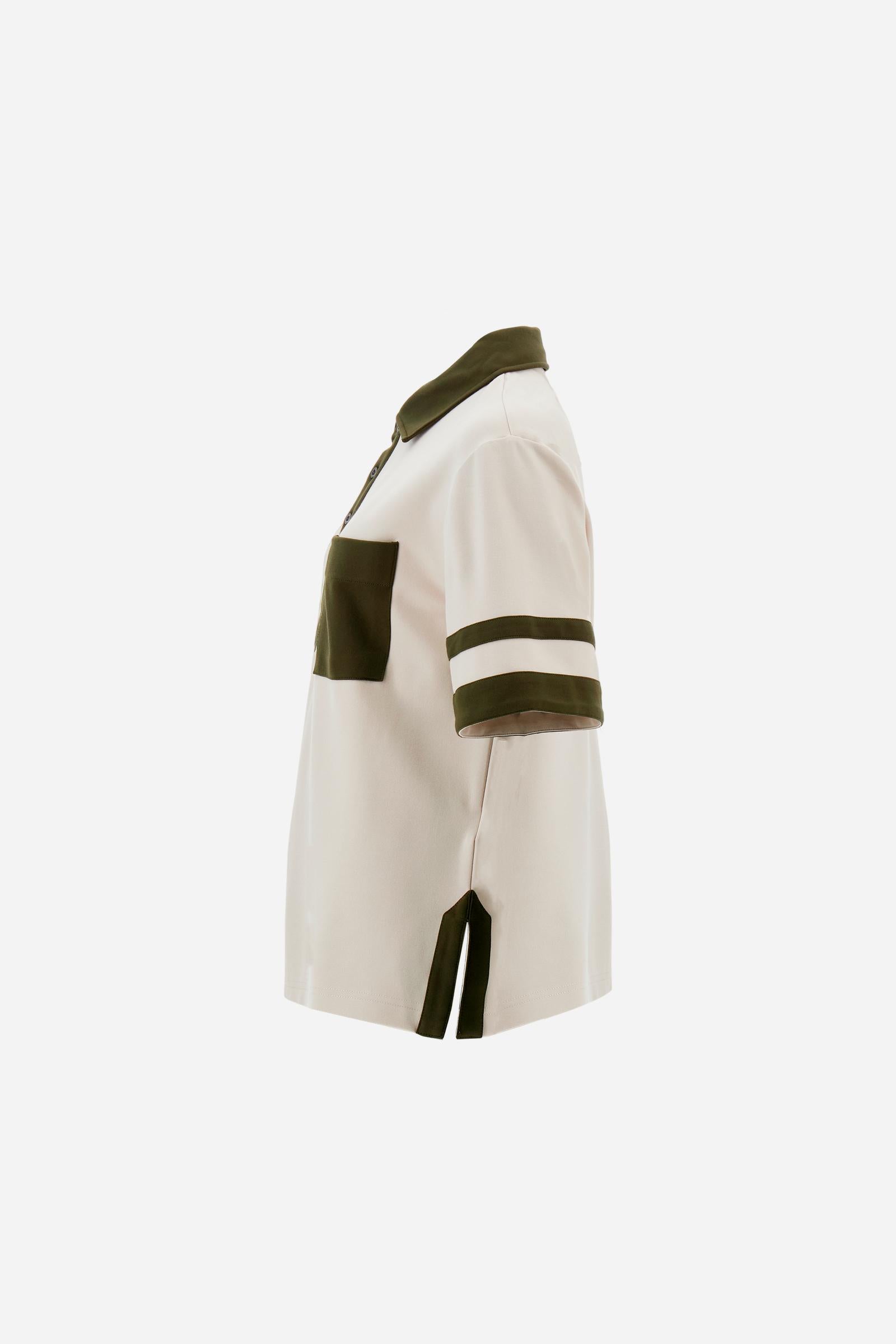 Women’s short-sleeve polo shirt in high-quality solid-colour viscose blend interlock. Classic collar with deep three-button placket, contrast fabric details on body and sleeves. Large embroidered logo on the back. Boxy, straight fit at the hips for a modern and comfortable silhouette. The model wears size L. - Creme Brulè/Kombu Gr