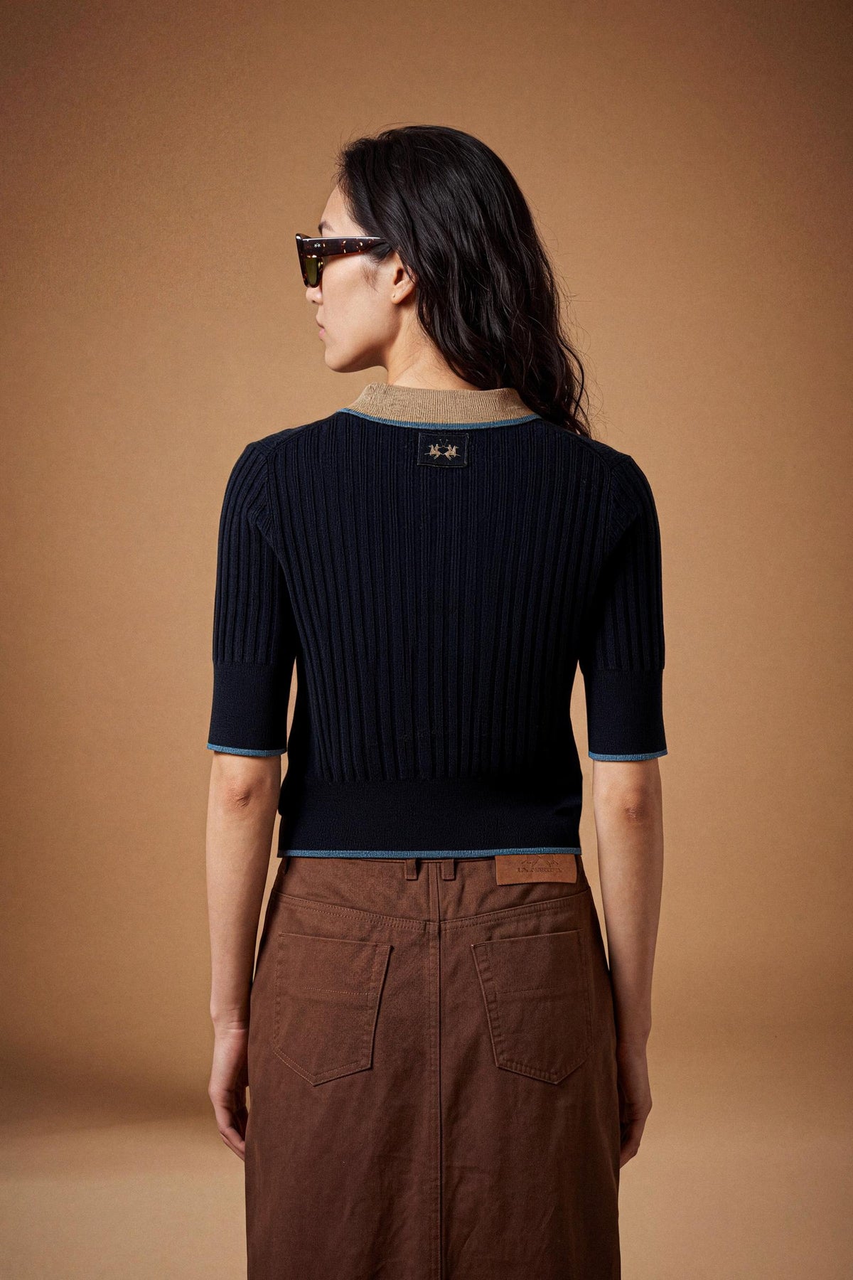 Slim-fit women's short-sleeve polo made from soft lambswool blend with vertical ribbing, ribbed collar, cuffs, and hem, featuring contrasting trims and a three-button front. - Navy